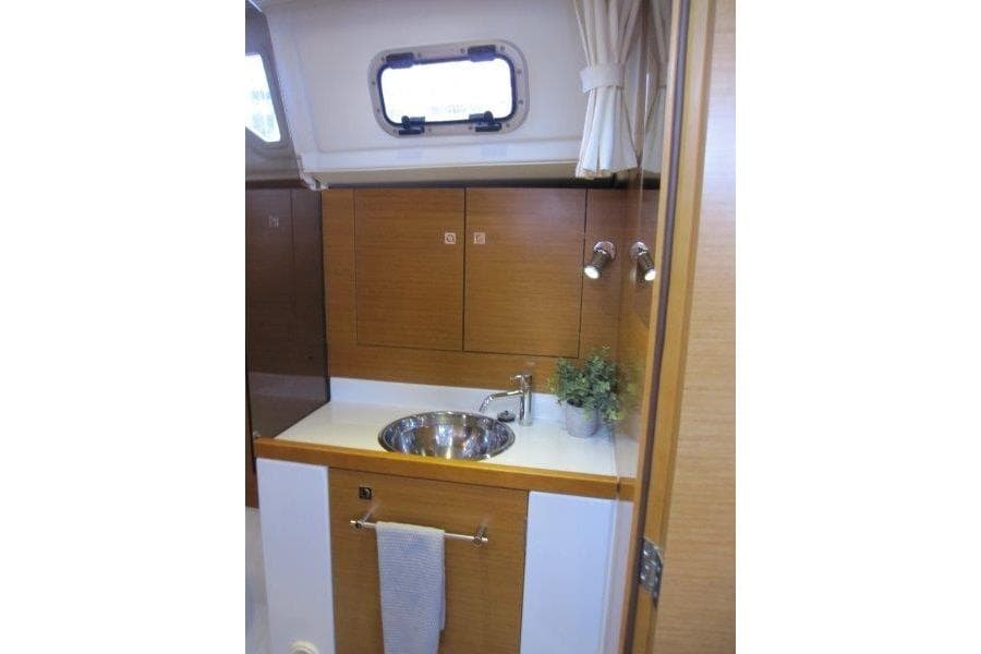 Interior of 2013 Jeanneau 379 sailboat bathroom with sink and storage cabinets.