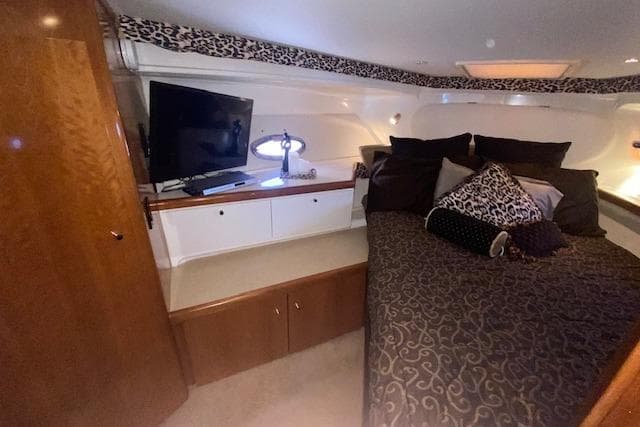 Luxurious cabin interior of 2002 Carver 350 Mariner with TV and patterned bedding.