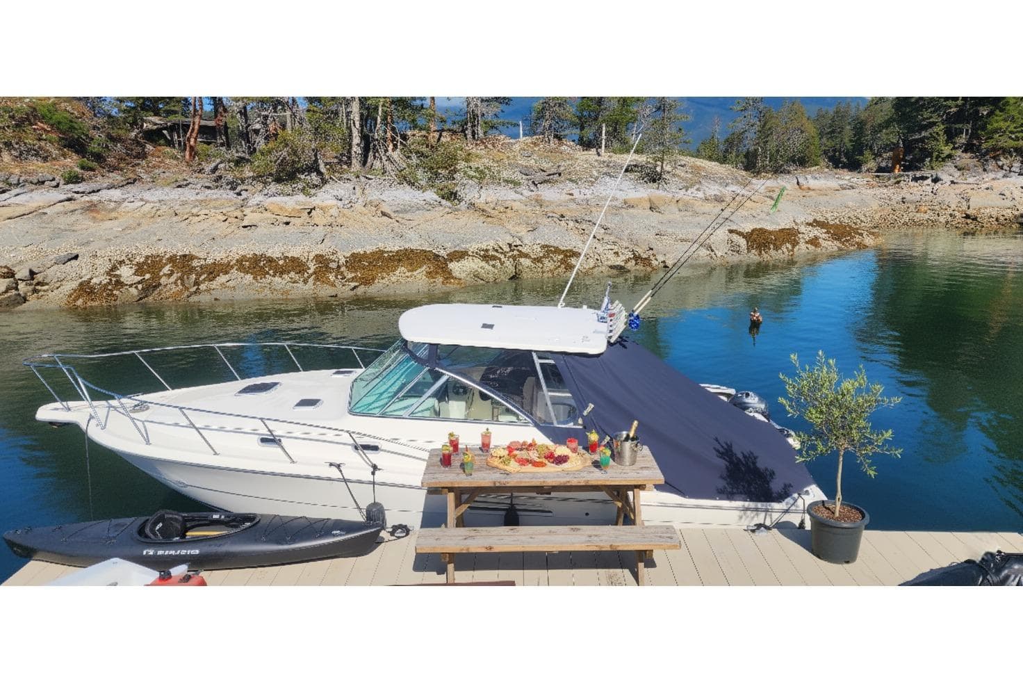 2000 Pursuit 3000 Express boat docked by a scenic rocky shoreline.