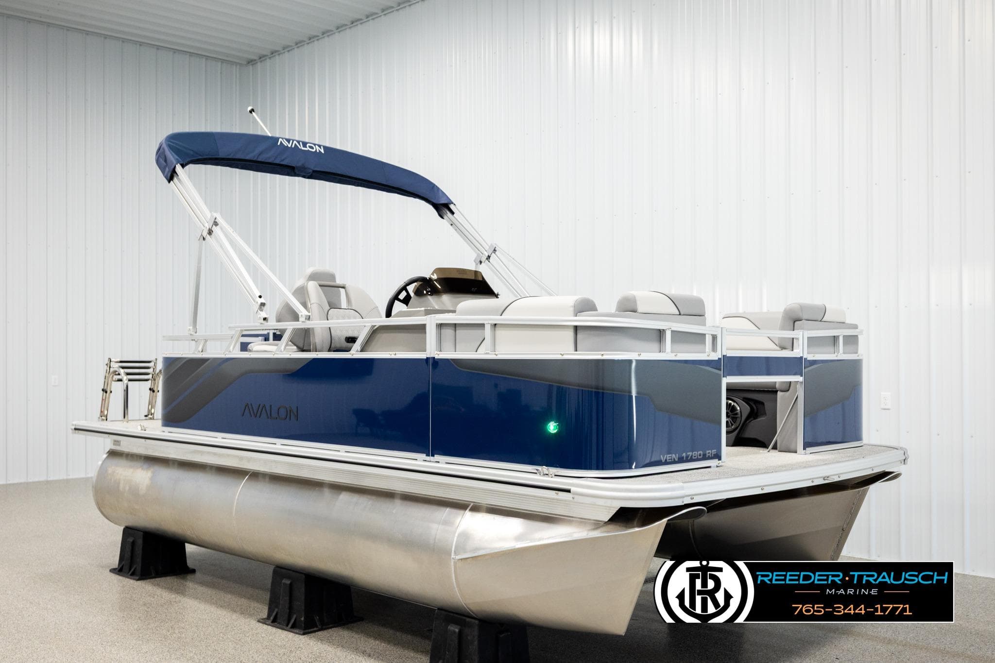 2026 Avalon VEN RF pontoon boat with blue exterior and canopy in showroom.