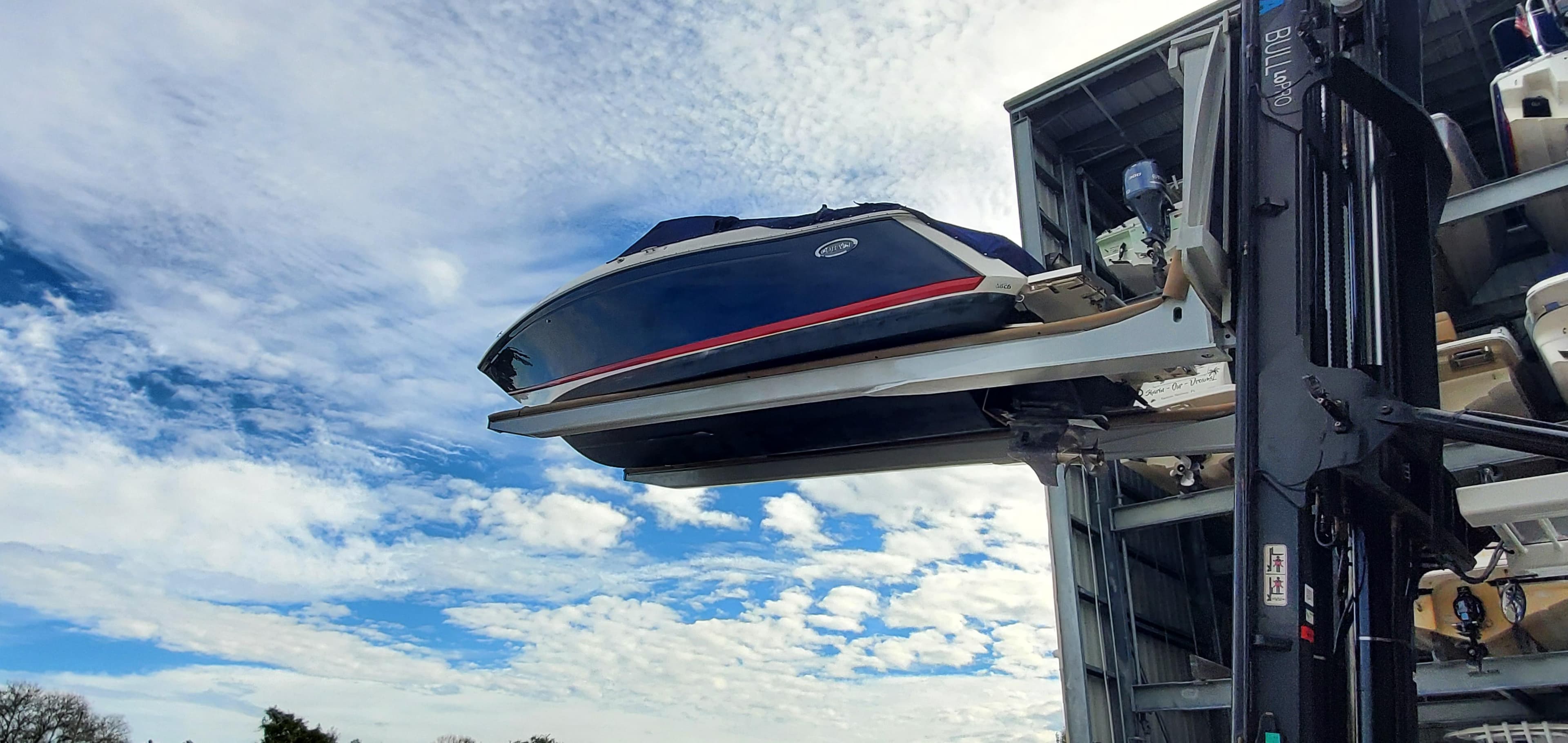 2013 Cobalt 24SD boat on forklift against a cloudy blue sky.
