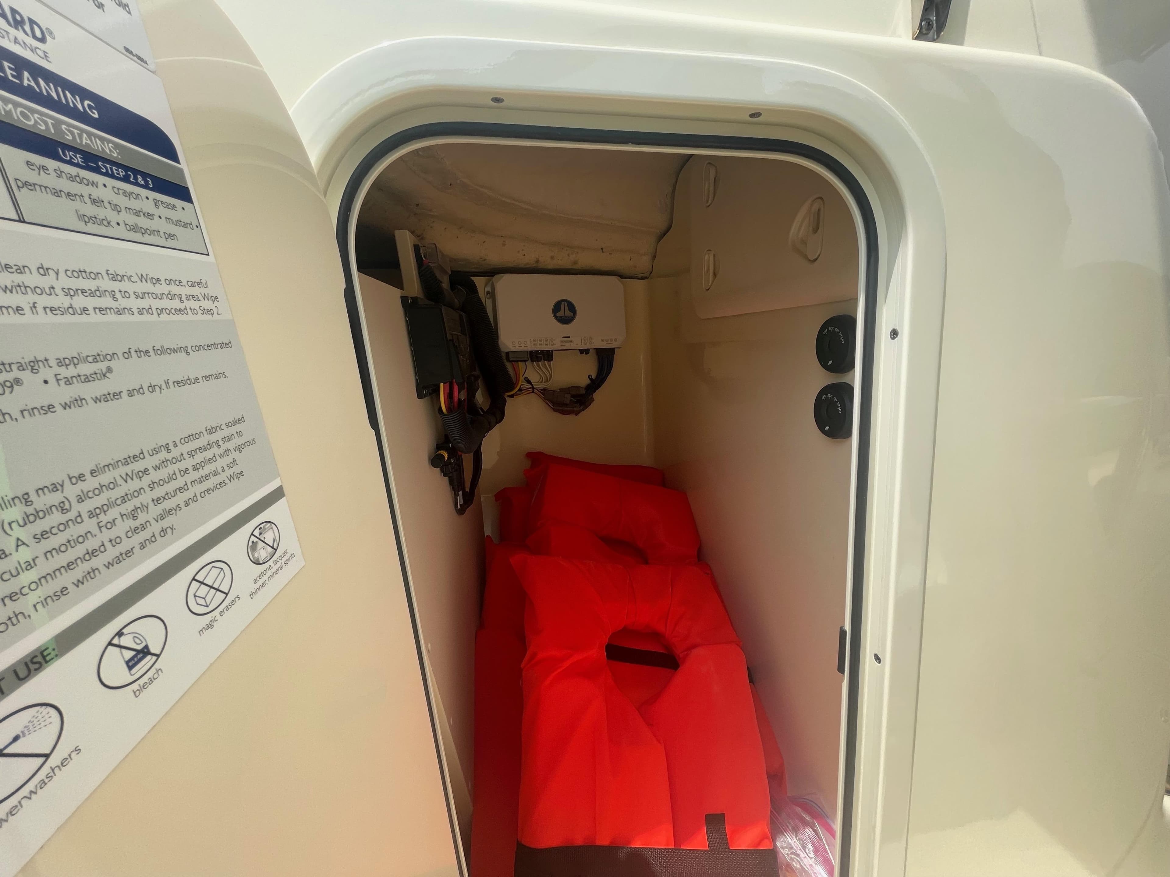 2023 Chris-Craft Calypso 28 storage compartment with red life jackets inside.
