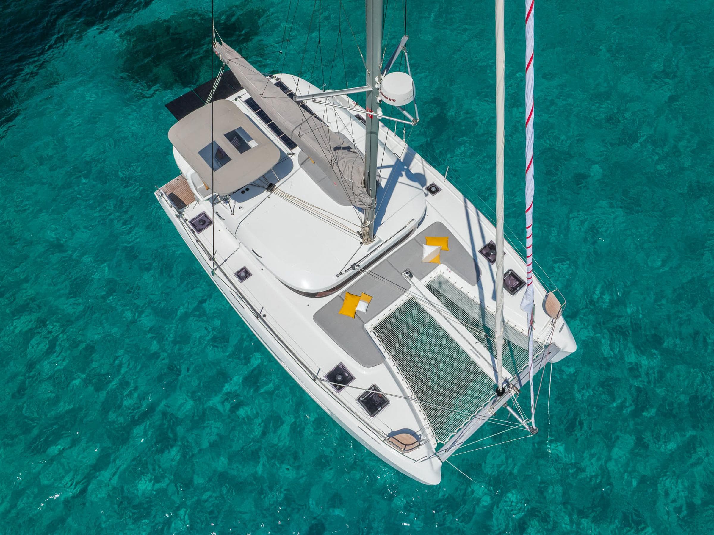 Aerial view of 2025 Lagoon 38 catamaran on clear turquoise water.