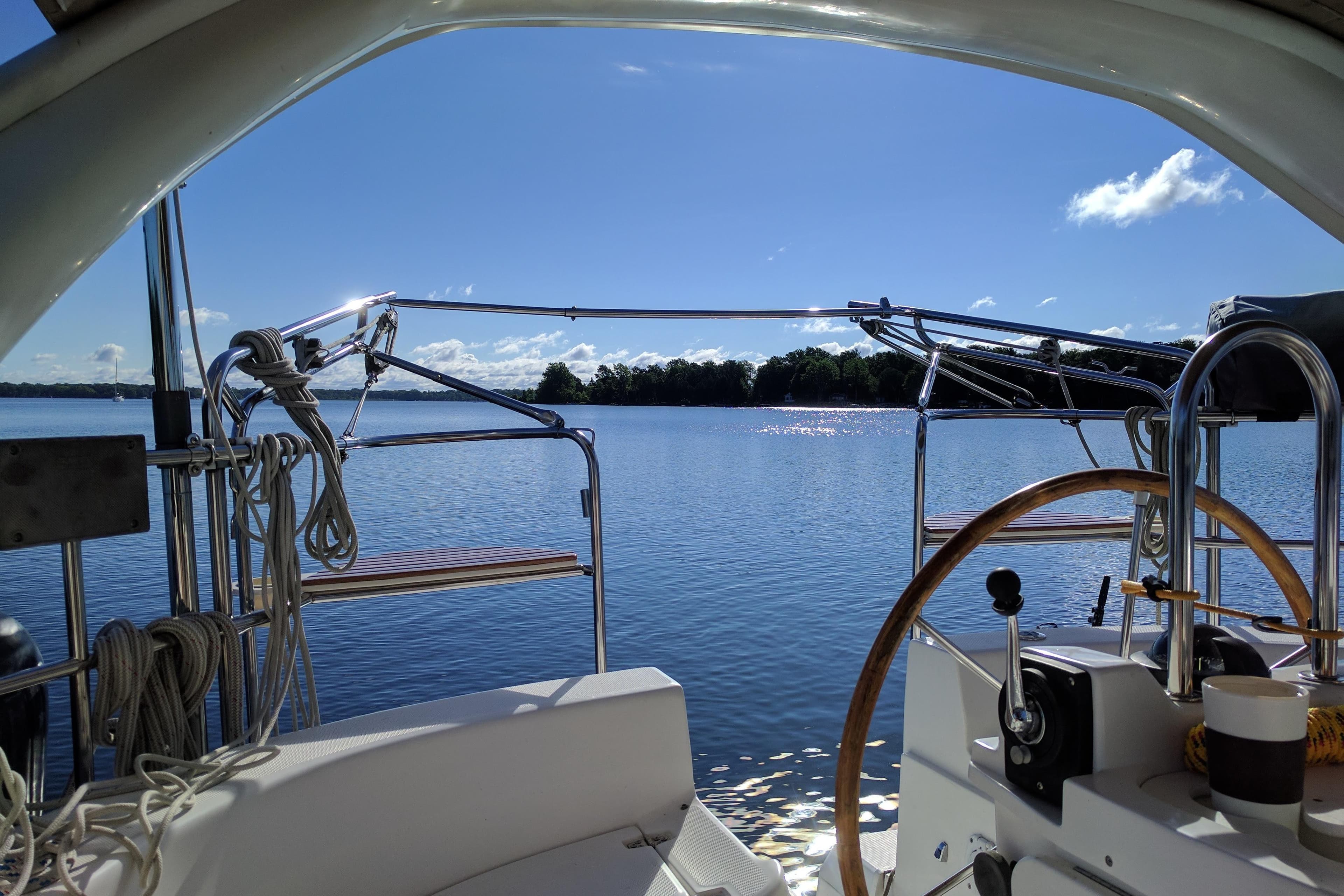 Cockpit view from a 1999 Hunter 410 sailboat on a sunny day, overlooking calm waters.
