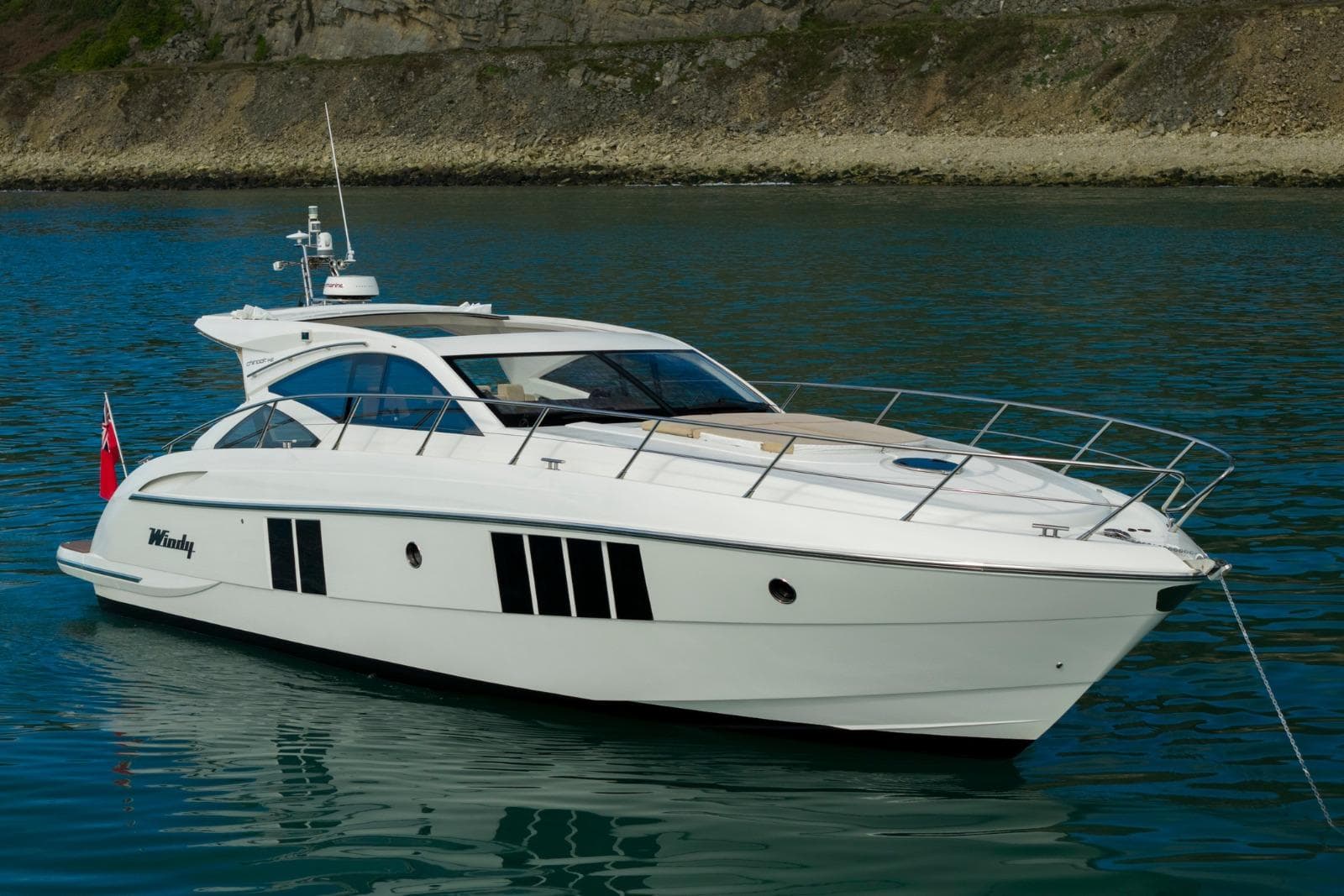2019 Windy 46 Chinook yacht on calm water near rocky shoreline.