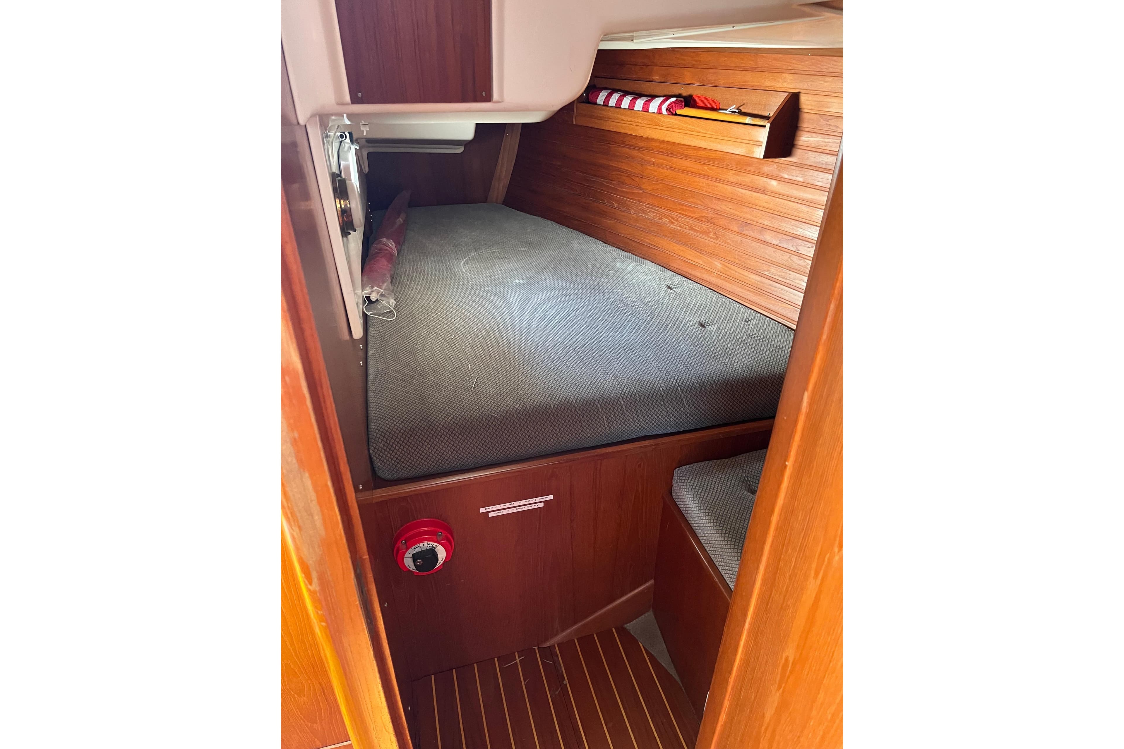 1986 Wauquiez Petorine cabin interior with wooden paneling and cushioned berth.