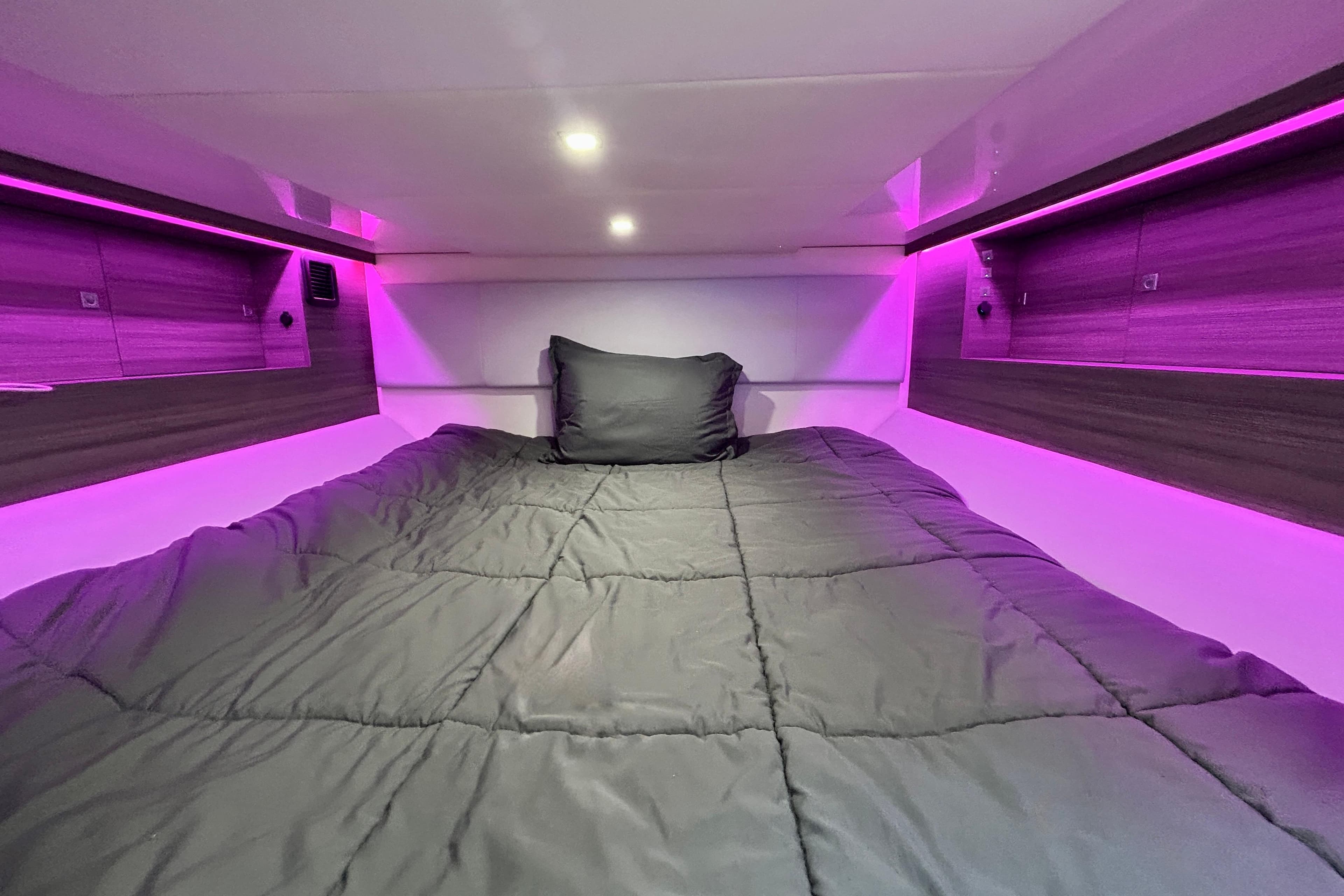 2022 Aviara AV40 OB cabin with cozy bed and ambient purple lighting.
