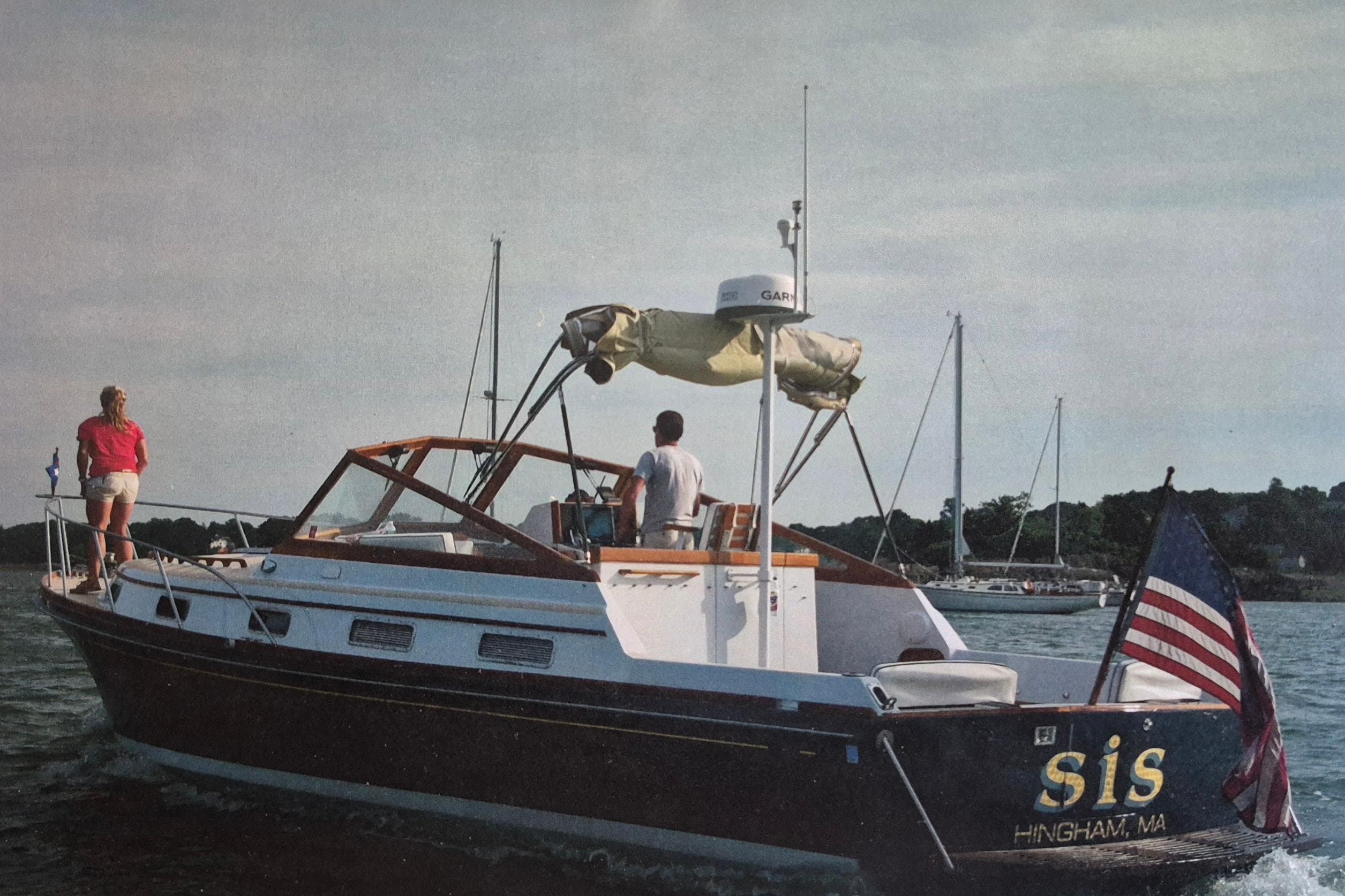 1990 Little Harbor Express boat on water, American flag, two people onboard, scenic background.