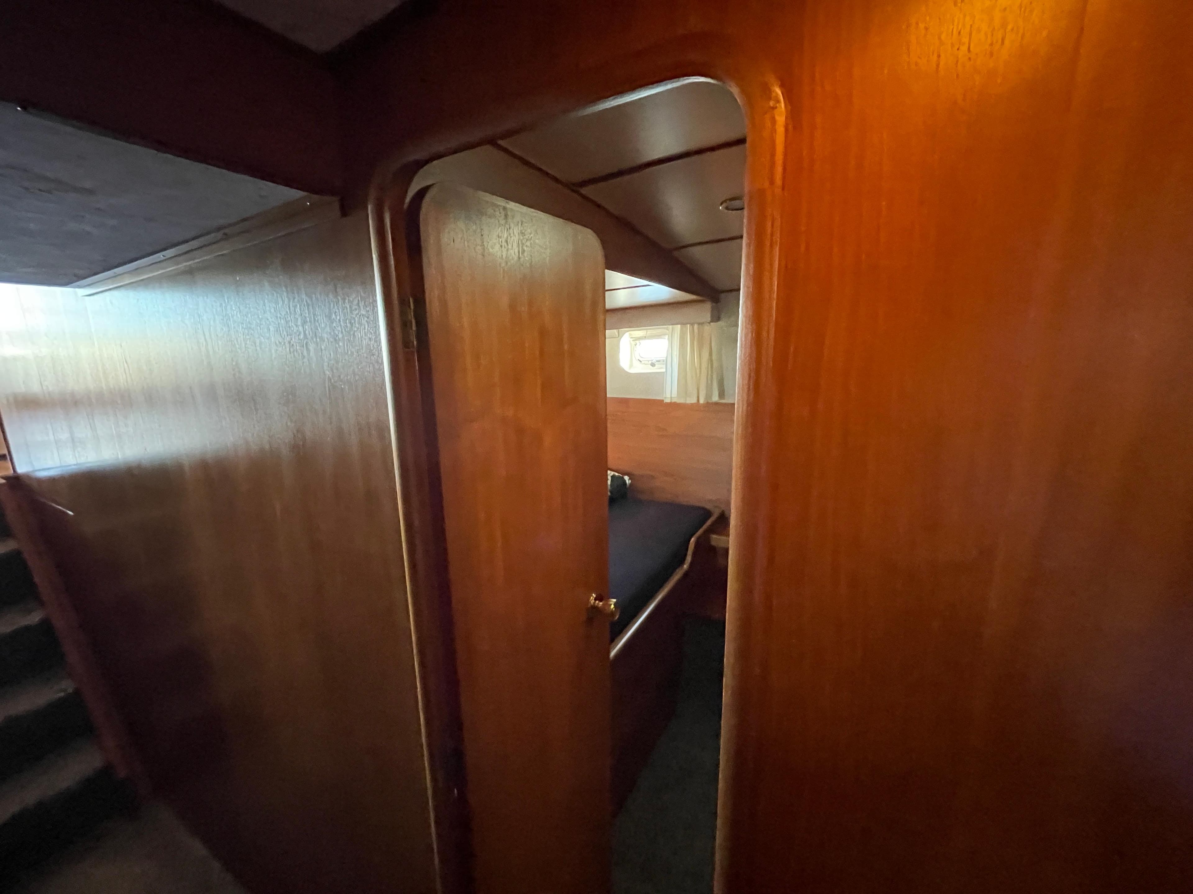 1986 Moody Trawler 50 interior cabin with wooden paneling and cozy sleeping area.