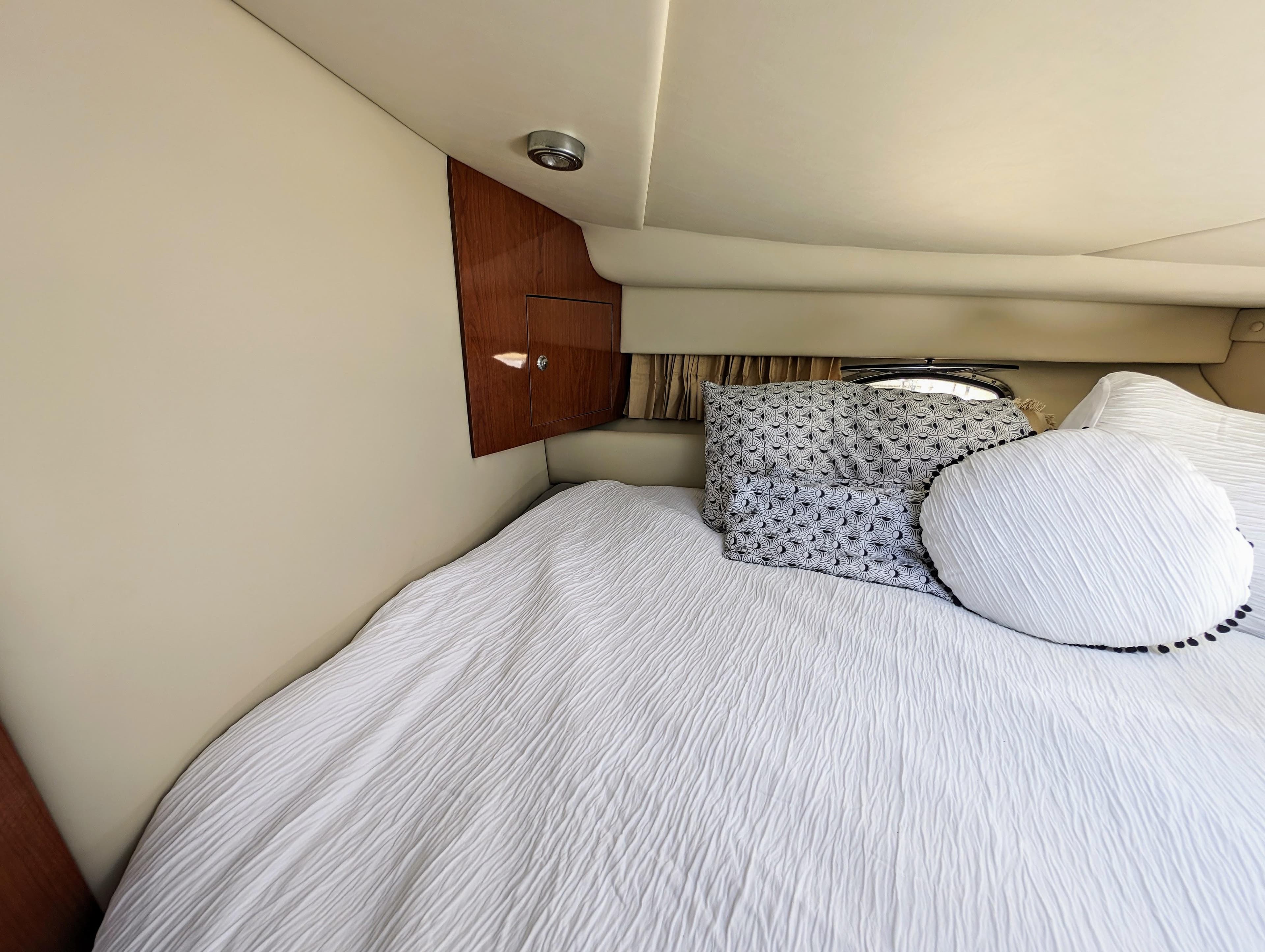 Cozy cabin interior of 2005 Regal 3560 yacht with plush bedding and wooden accents.