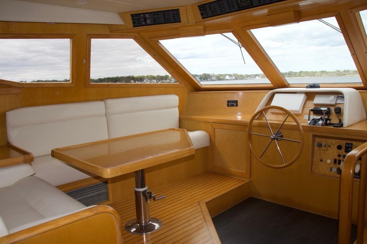 Interior of 2002 McKinna 57 Pilothouse yacht with wooden helm and seating area.