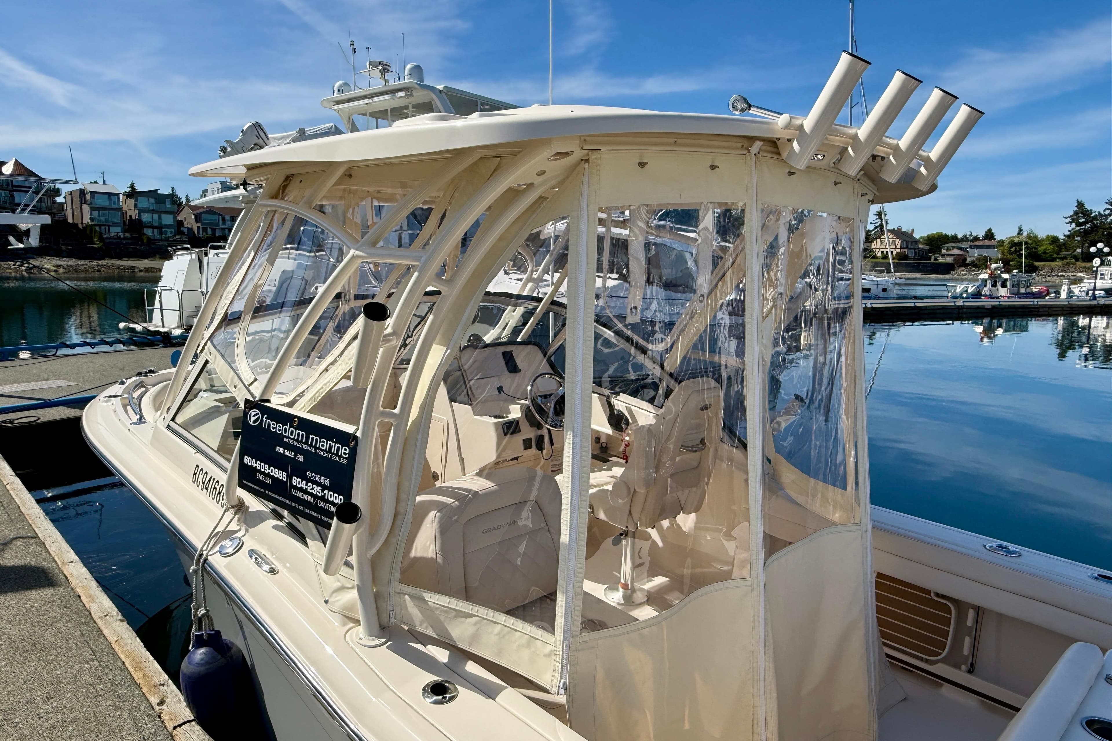 2023 Grady-White Freedom 235 boat docked at marina, clear enclosure, sunny day.
