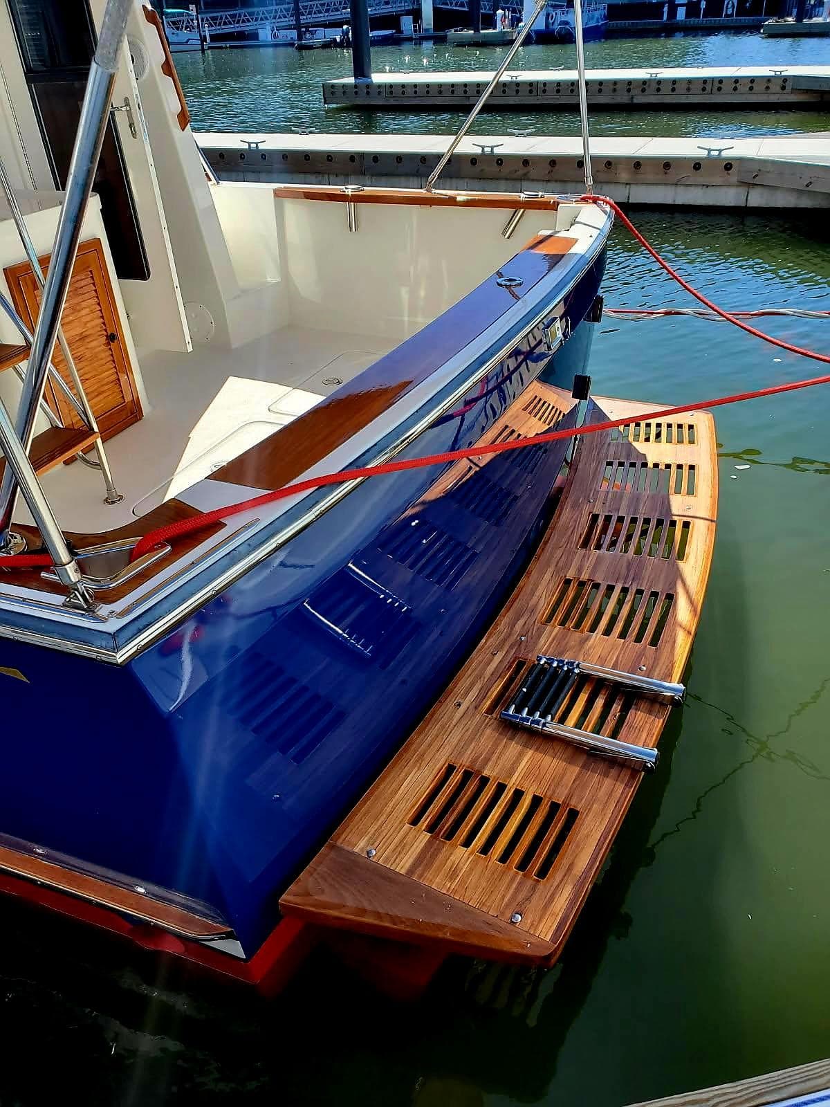 2004 Sabre 36 Flybridge Fast Trawler docked, featuring a wooden swim platform and blue hull.