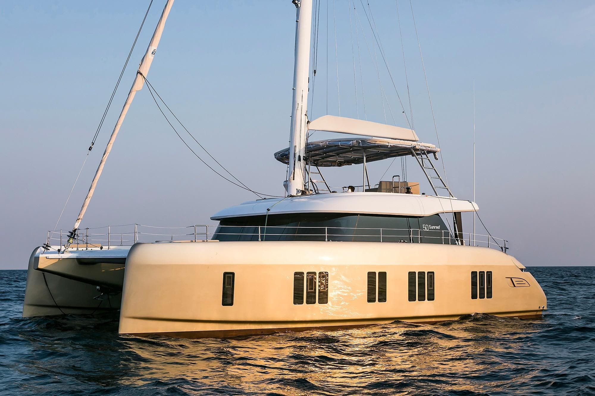 2026 Sunreef 50 catamaran sailing on calm sea at sunset.