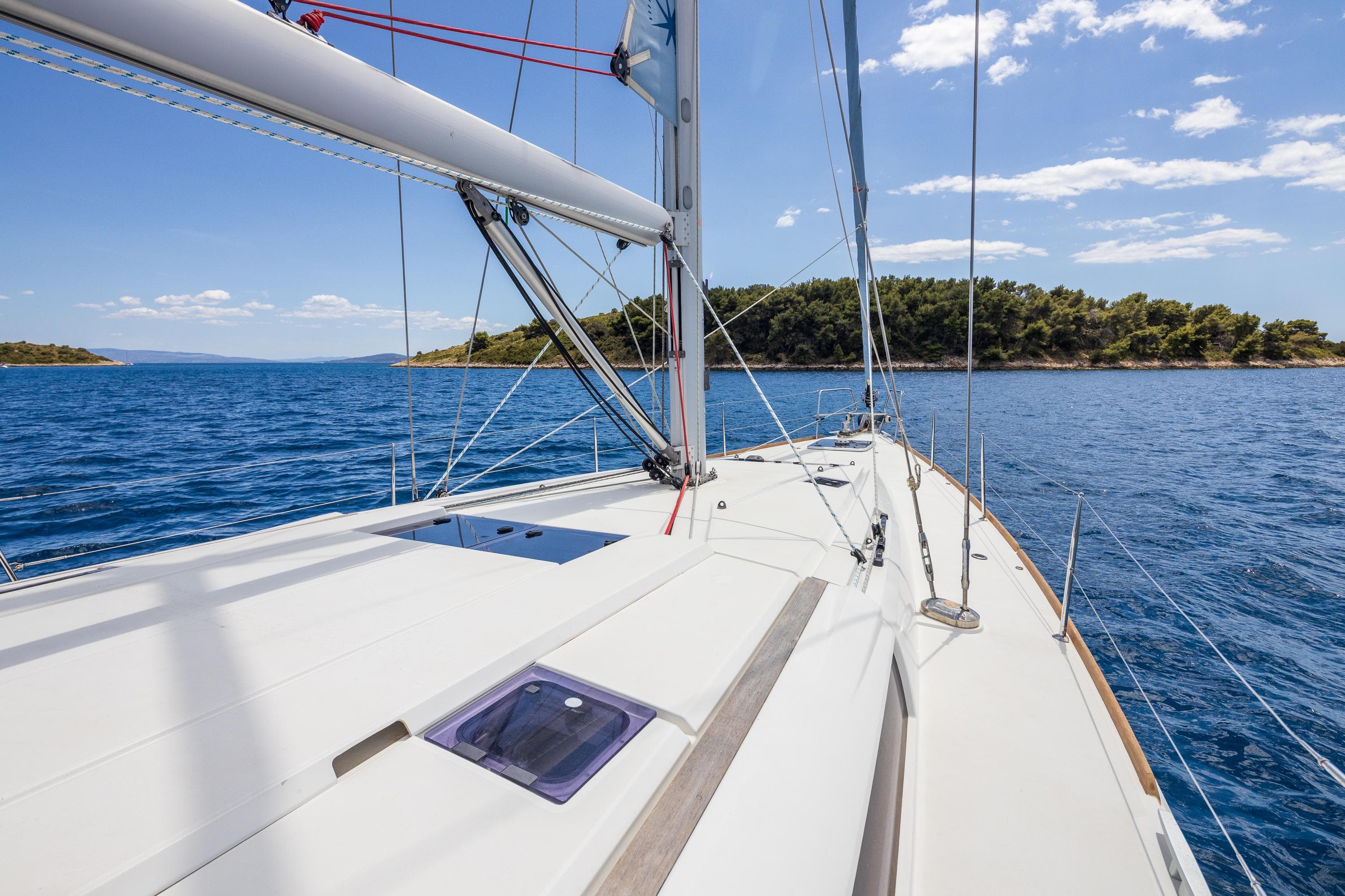 2018 Jeanneau Sun Odyssey 519 sailing on clear blue waters near a lush island.