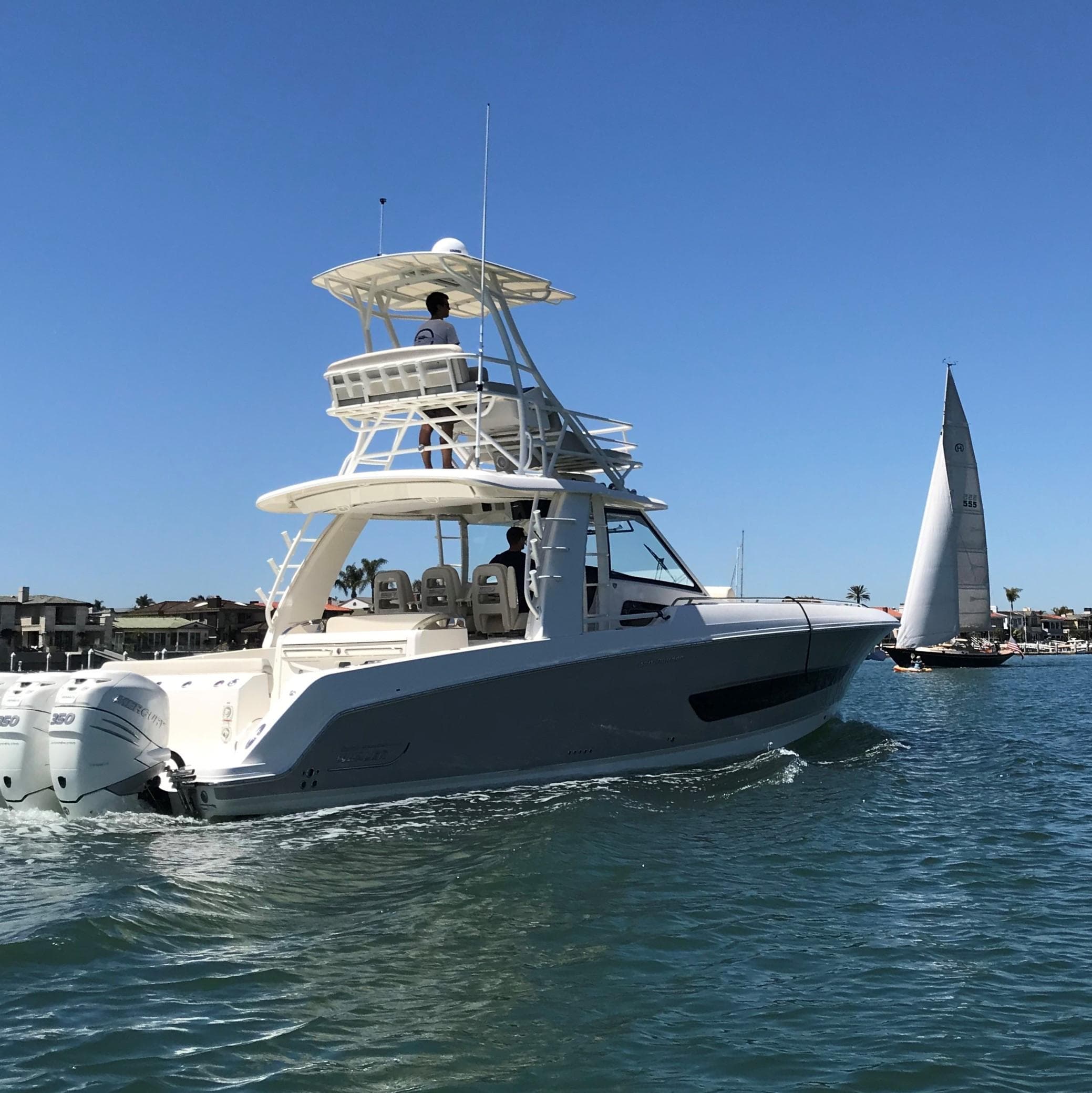 2018 Boston Whaler 420 Outrage cruising on a sunny day with a sailboat in the background.