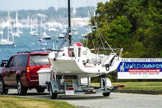 Red SUV towing 2026 J Boats J/70 sailboat at Newport World Championship event.