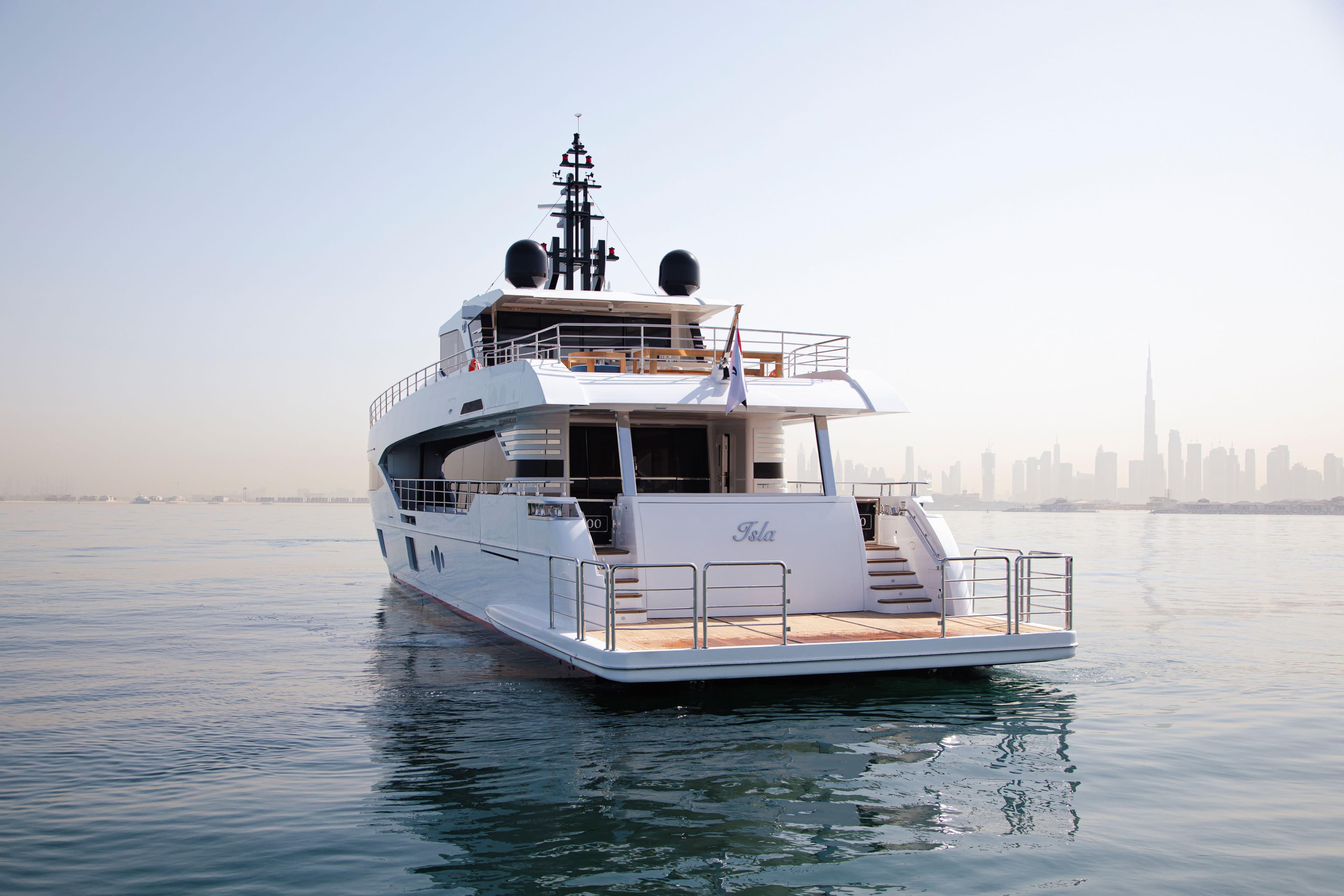 Majesty 100 yacht, 2025 model, cruising near a city skyline on calm waters.