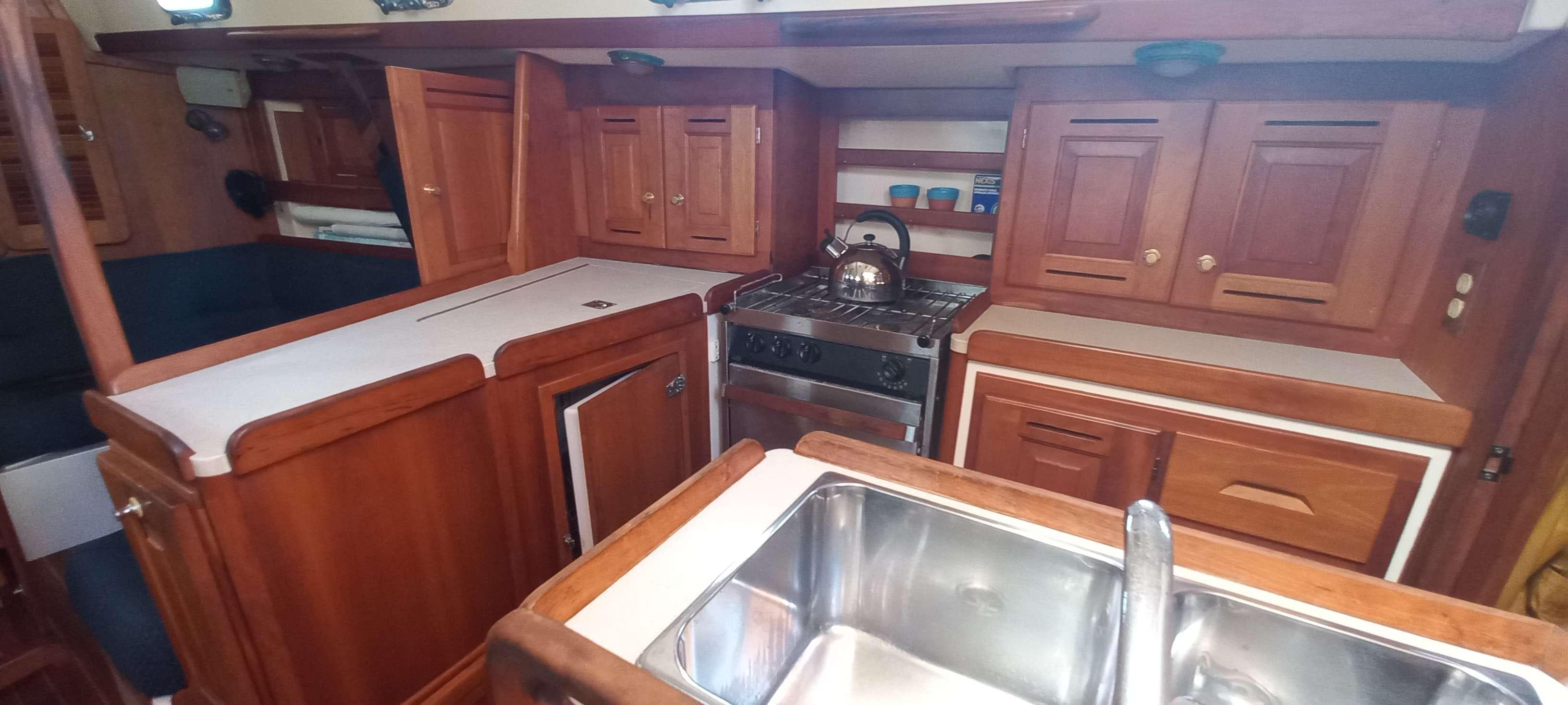 2003 Tartan 3700 yacht interior kitchen with wooden cabinets and stainless steel sink.