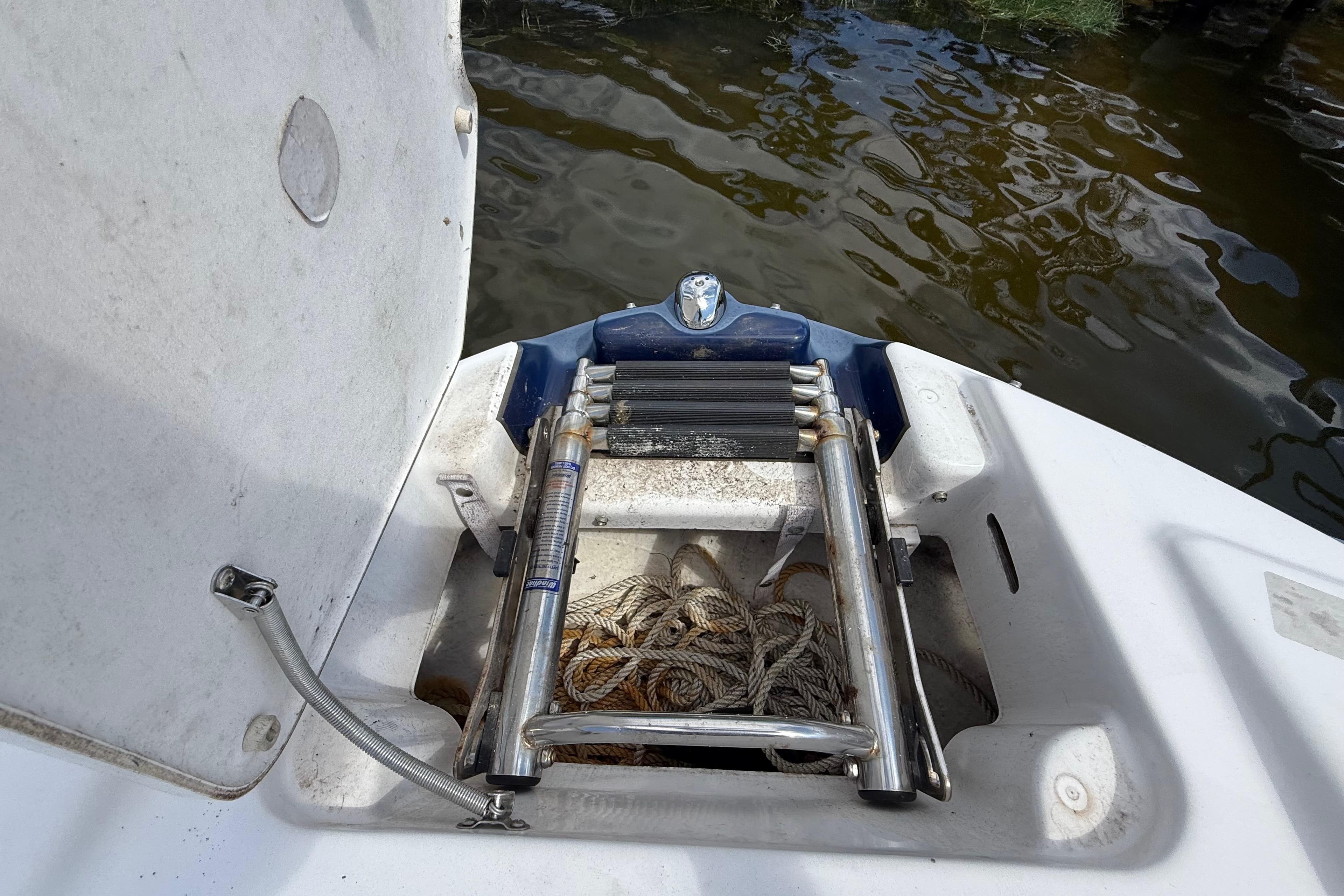 2014 Yamaha Boats 242 Limited S ladder compartment with rope, near water.