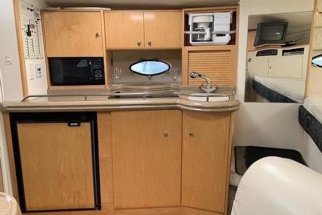 2002 Larson 330 boat interior kitchen with wood cabinets, sink, and appliances.