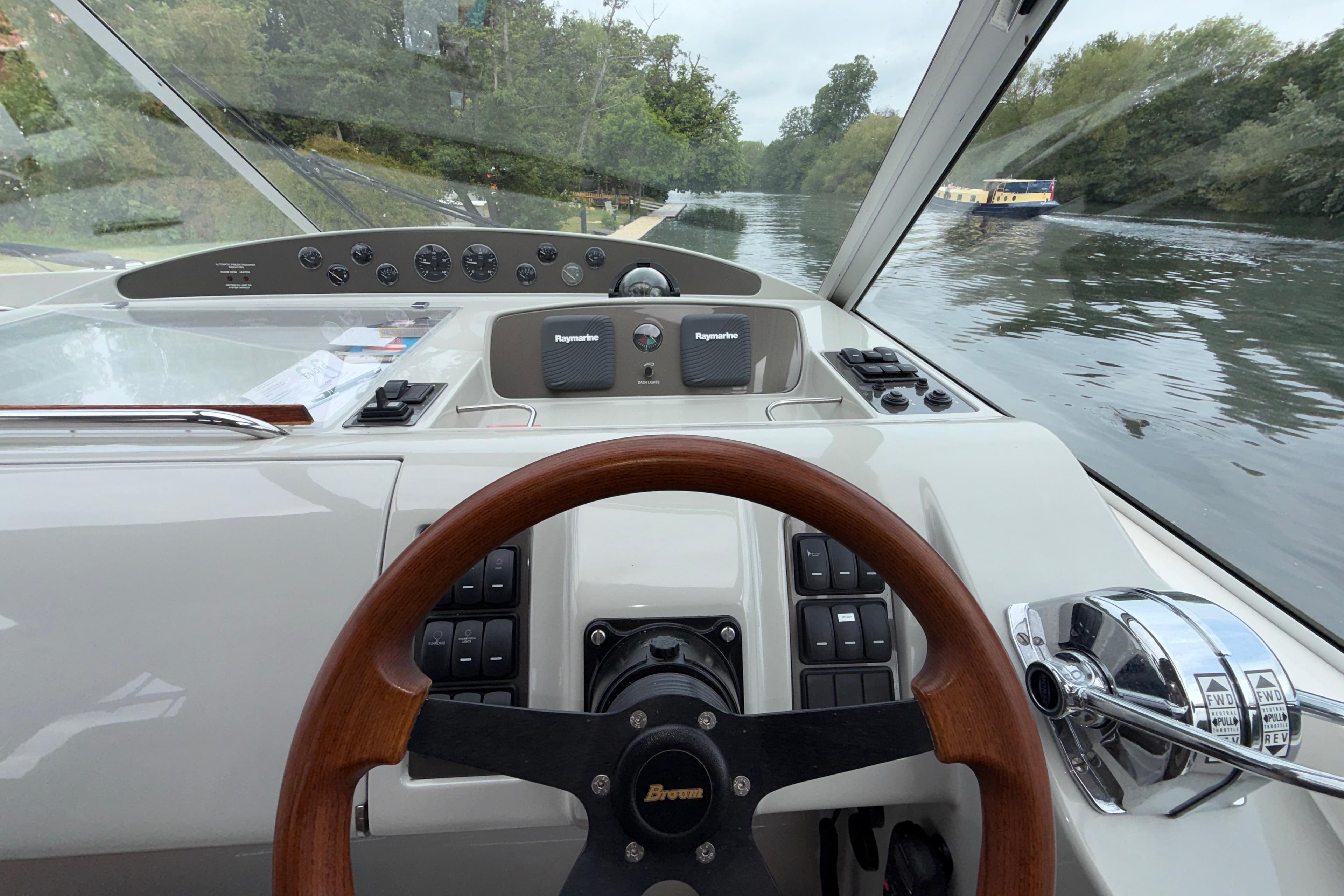 Steering wheel and dashboard of a 2004 Broom 42 CL boat on a river.