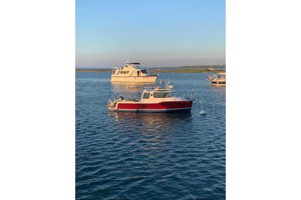 2022 Ranger Tugs R-25 boat anchored on calm water at sunset.