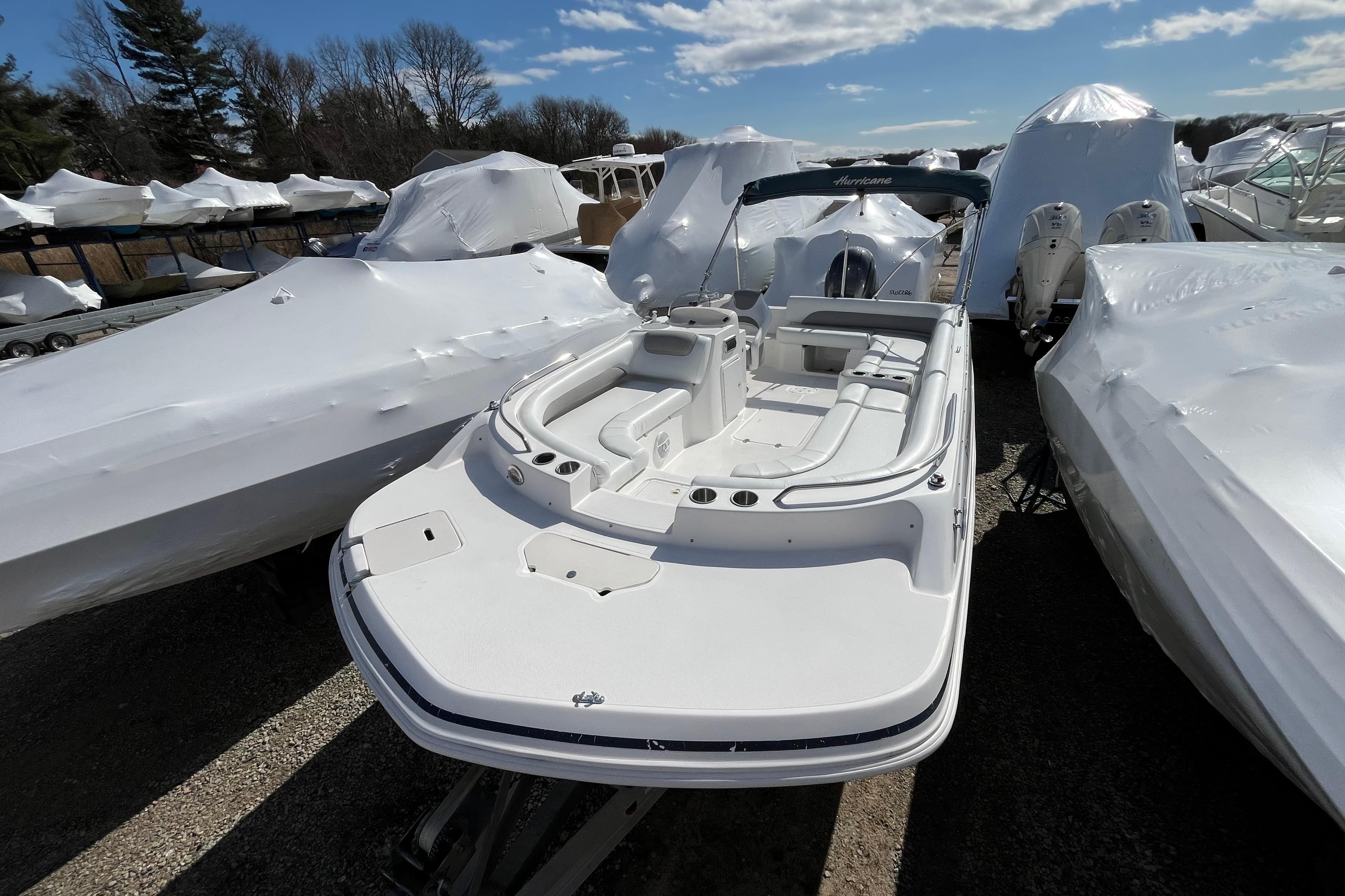 2015 Hurricane SunDeck Sport 201 OB boat in storage, surrounded by covered vessels.