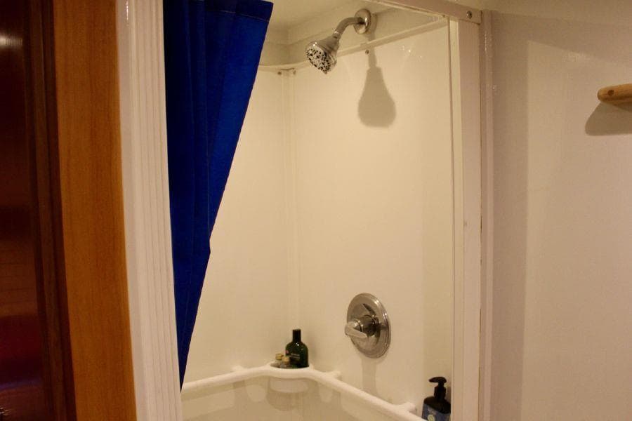 Shower area in 2017 Bruce Roberts 54' Ketch with blue curtain and toiletries.