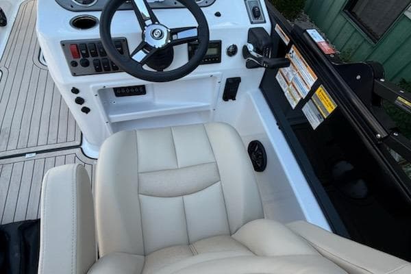 2026 Hurricane FD198RE-OB boat cockpit with steering wheel and beige seating.