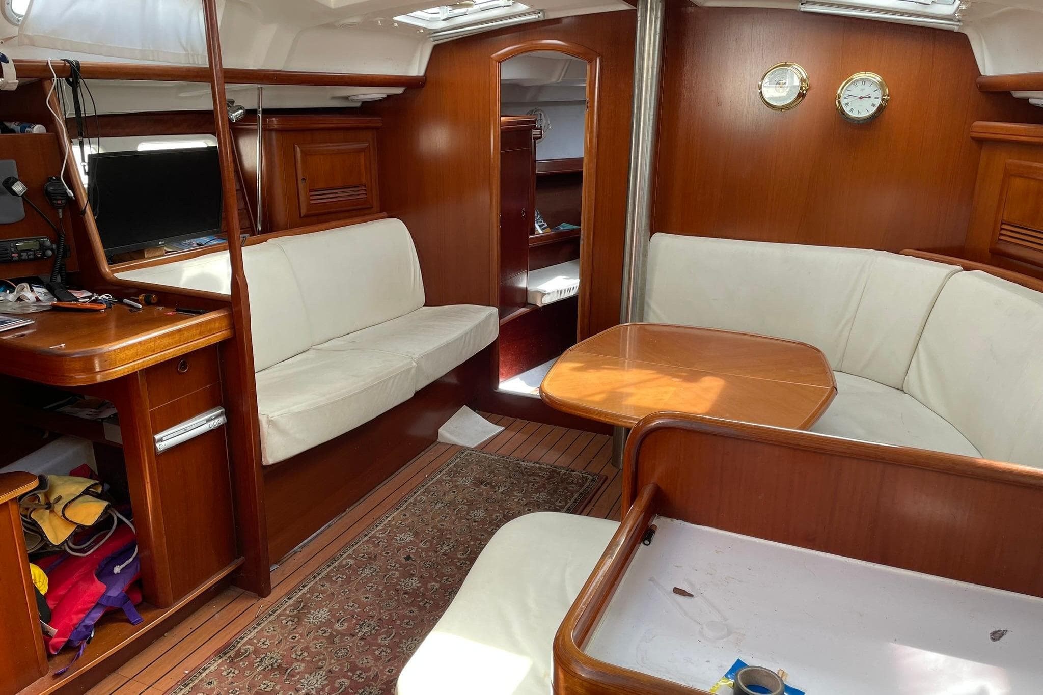 Interior of 2003 Beneteau 423 yacht with wooden furnishings and white seating.