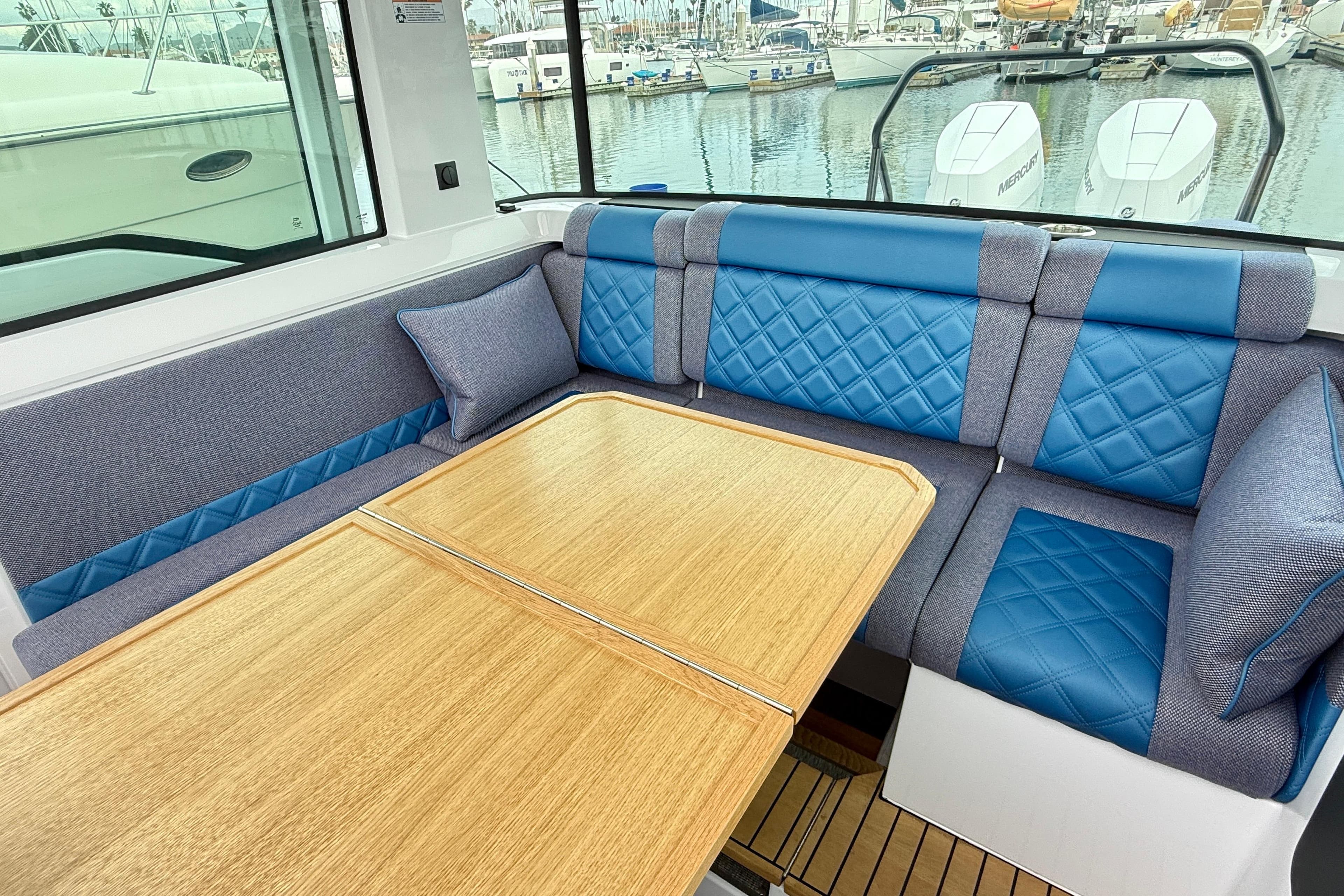 2025 Axopar 37 XC Cross Cabin interior with blue quilted seating and wooden table.