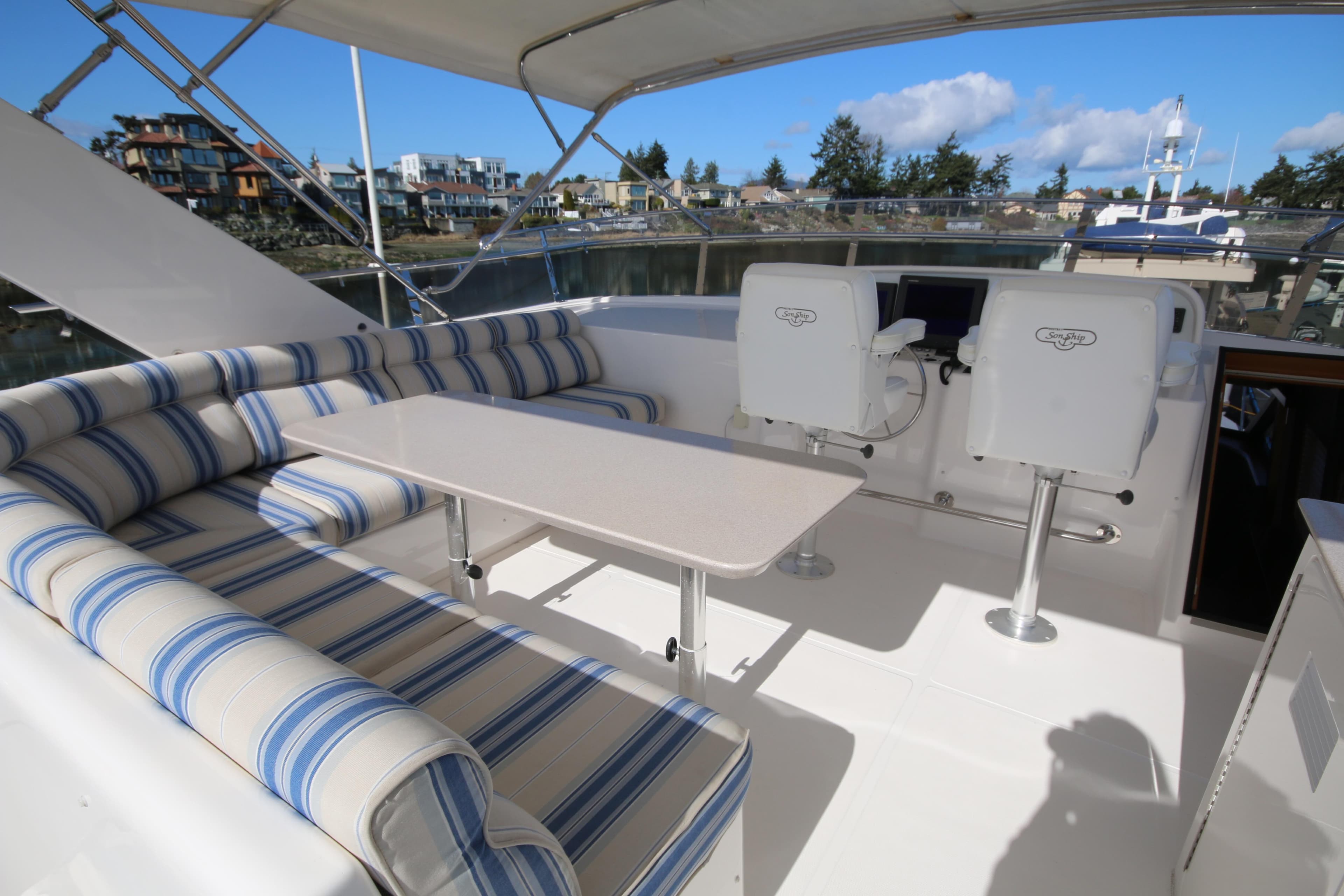 Luxurious 2004 West Bay 68 Sonship Pilothouse yacht interior with striped seating and helm chairs.