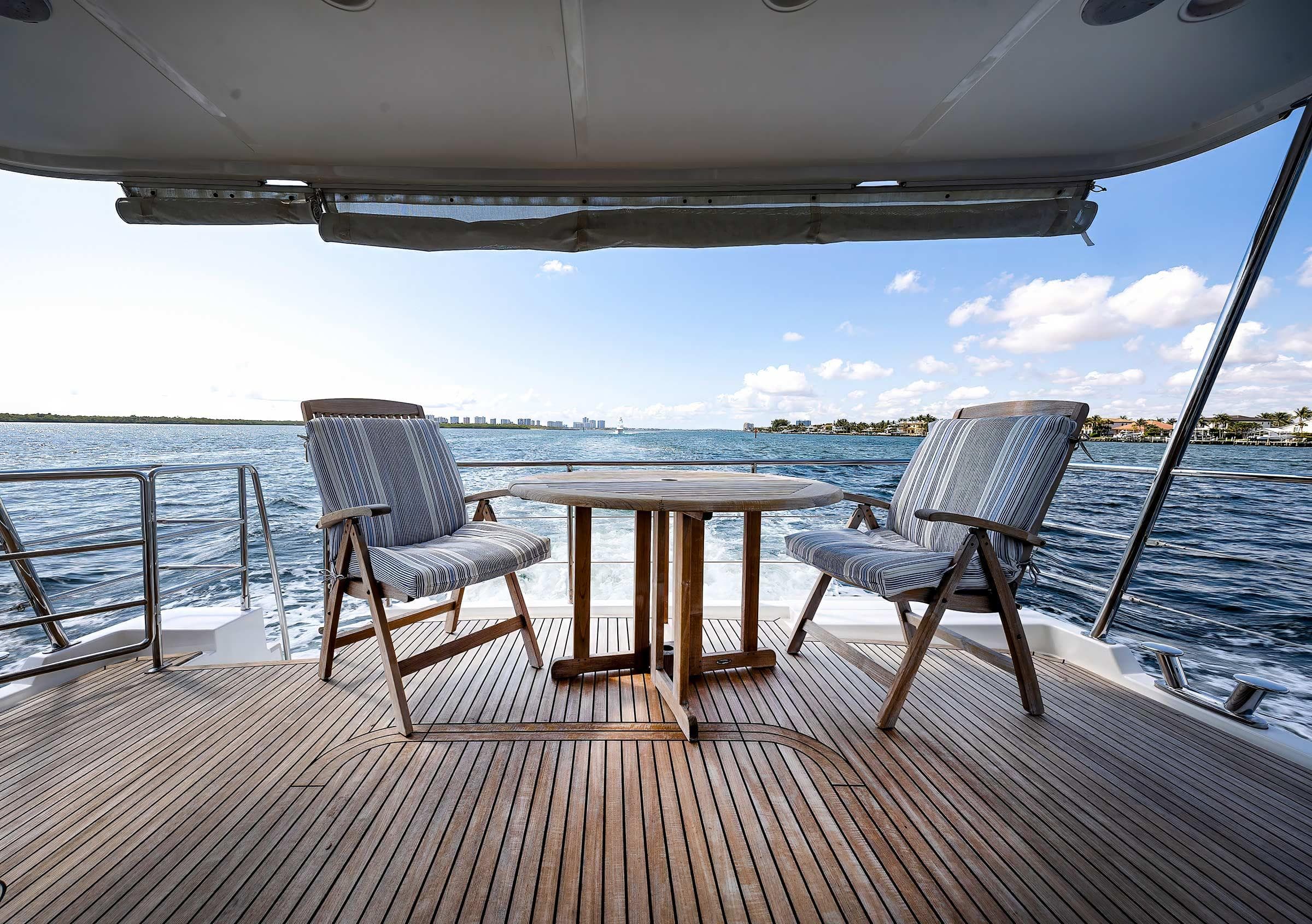 2019 Nordhavn 59 Coastal Pilot yacht deck with chairs and table, overlooking serene ocean view.