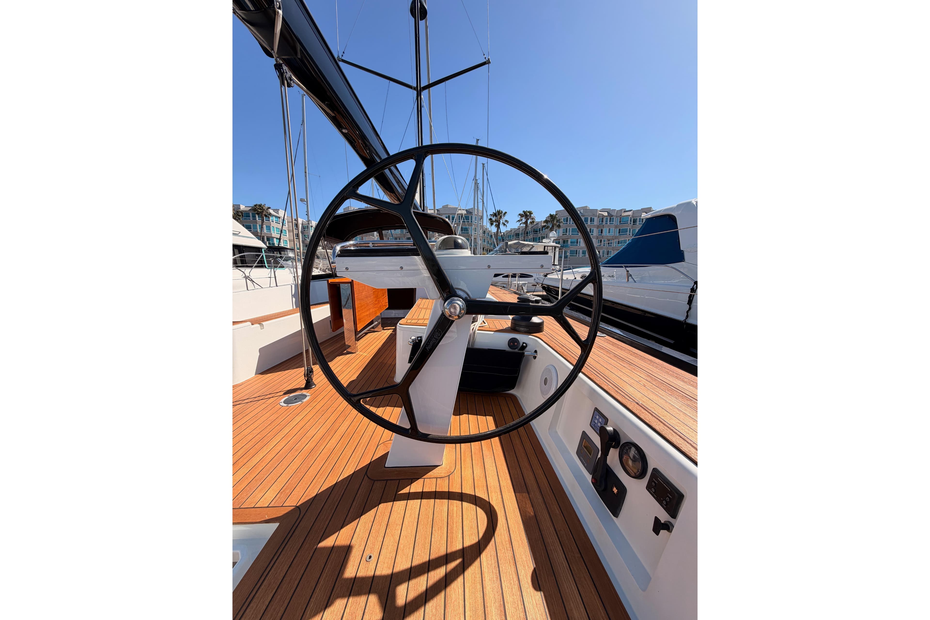 Steering wheel of a 2017 Solaris 50 yacht, docked in a sunny marina.