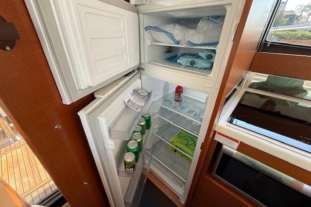 Open refrigerator on 2015 Prestige 500 yacht, stocked with drinks and ice.