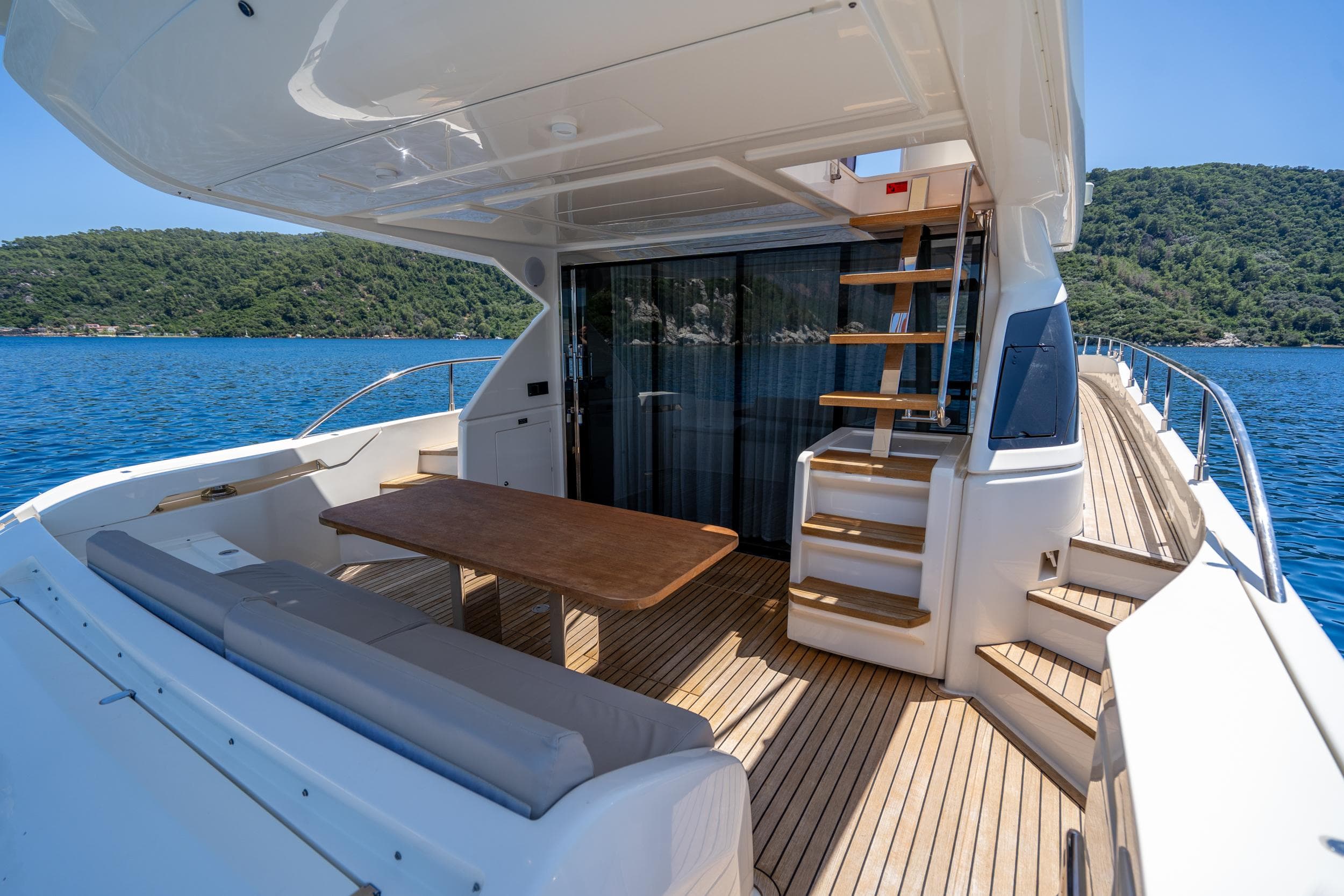 Luxurious 2021 Ferretti Yachts 550 deck with seating, table, and scenic ocean view.