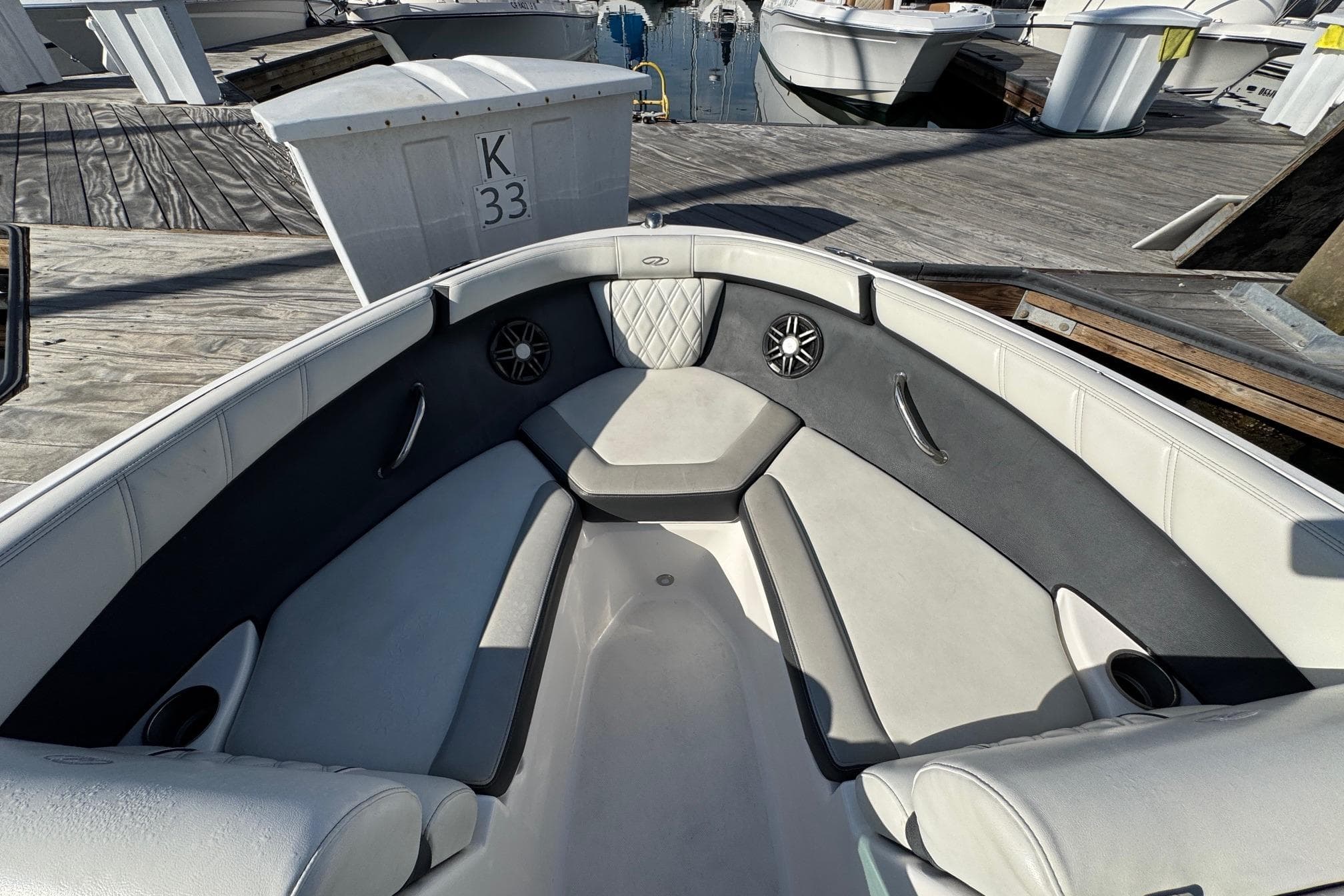2024 Regal 21 OBX boat interior with cushioned seating and speakers at a dock.