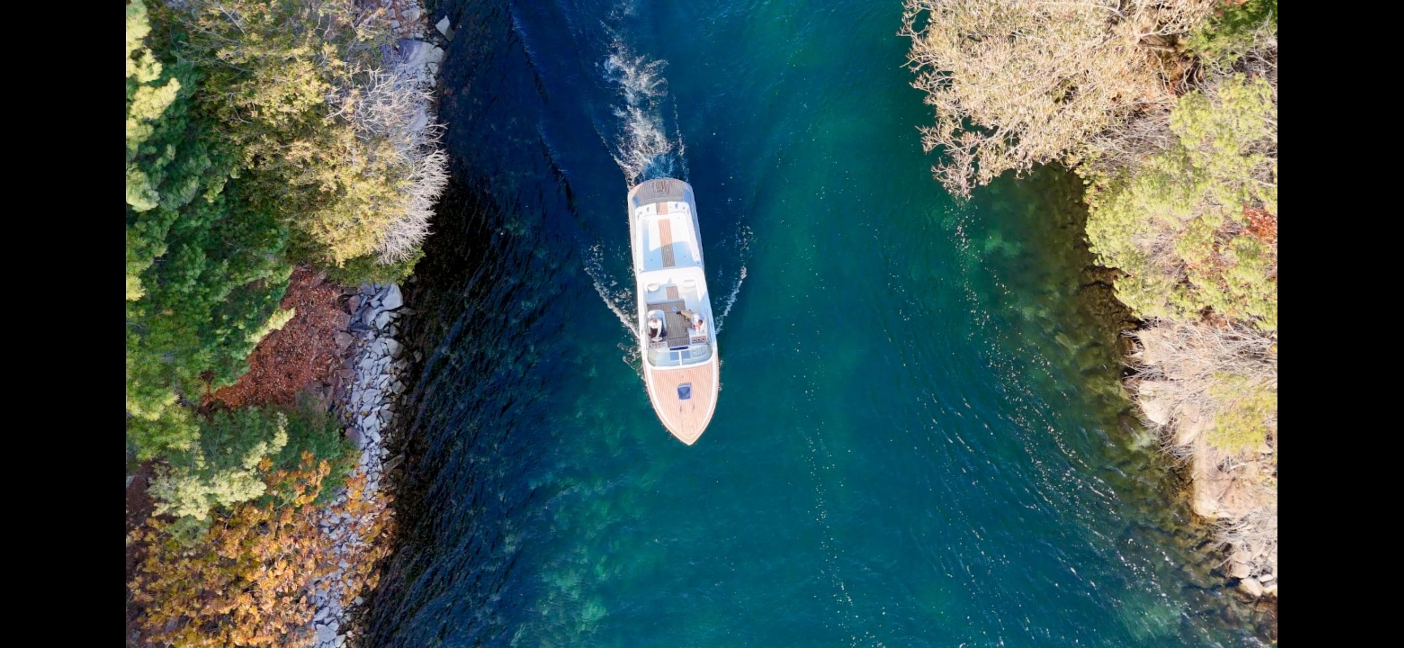 Aerial view of 2024 Comitti Venezia V28 boat navigating through a narrow, tree-lined waterway.