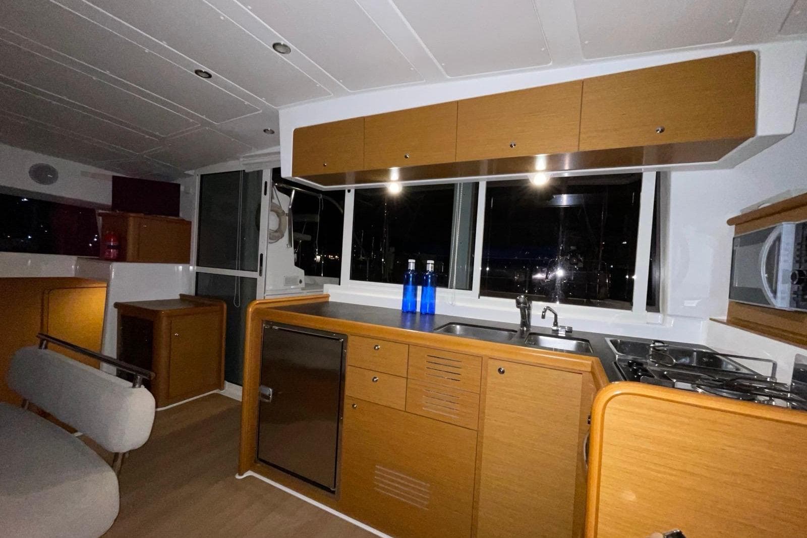 Interior of 2016 Lagoon 421 yacht kitchen with wooden cabinets and modern appliances.