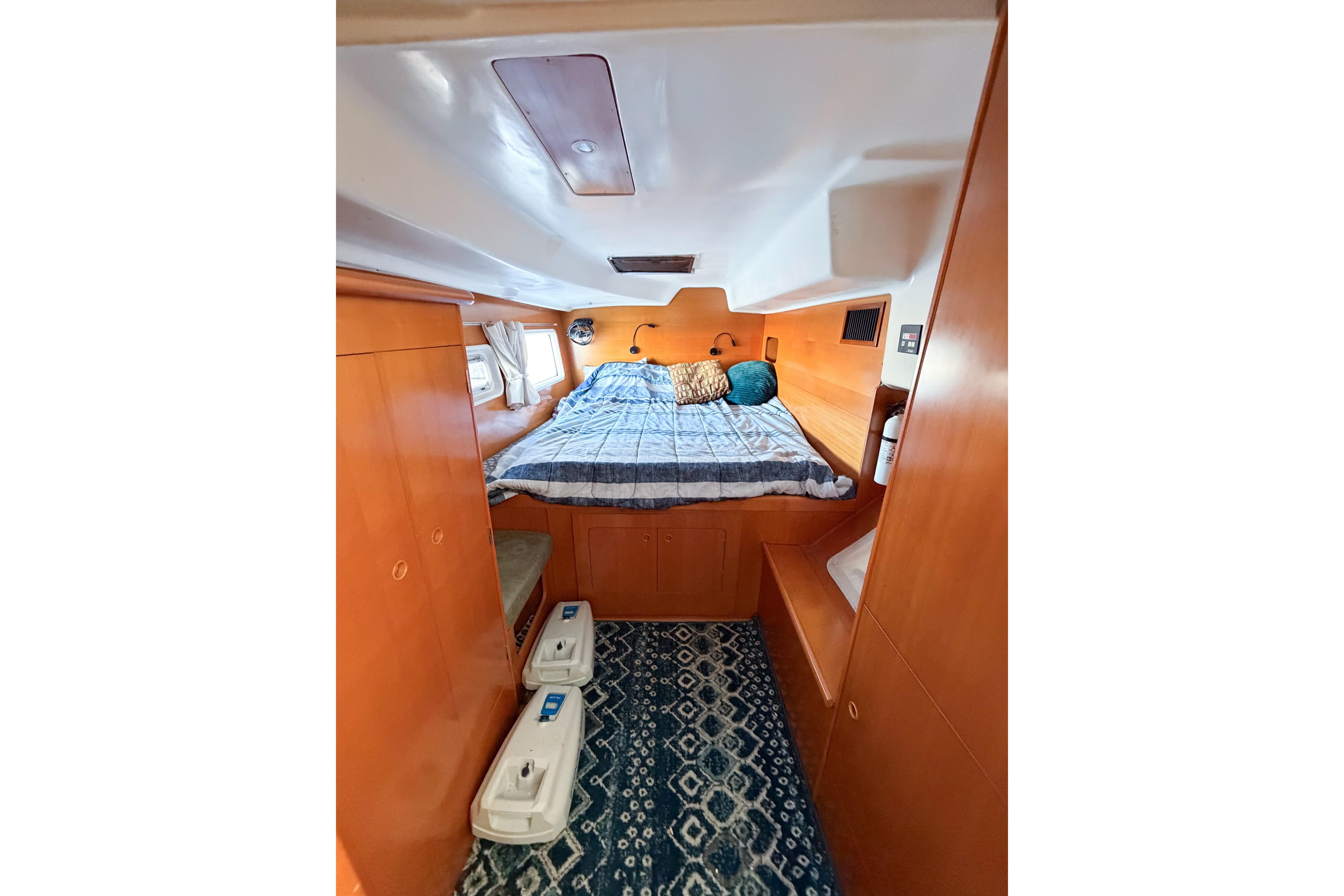 Cozy cabin interior of 2005 Lagoon 380 S2 catamaran with bed and wooden furnishings.