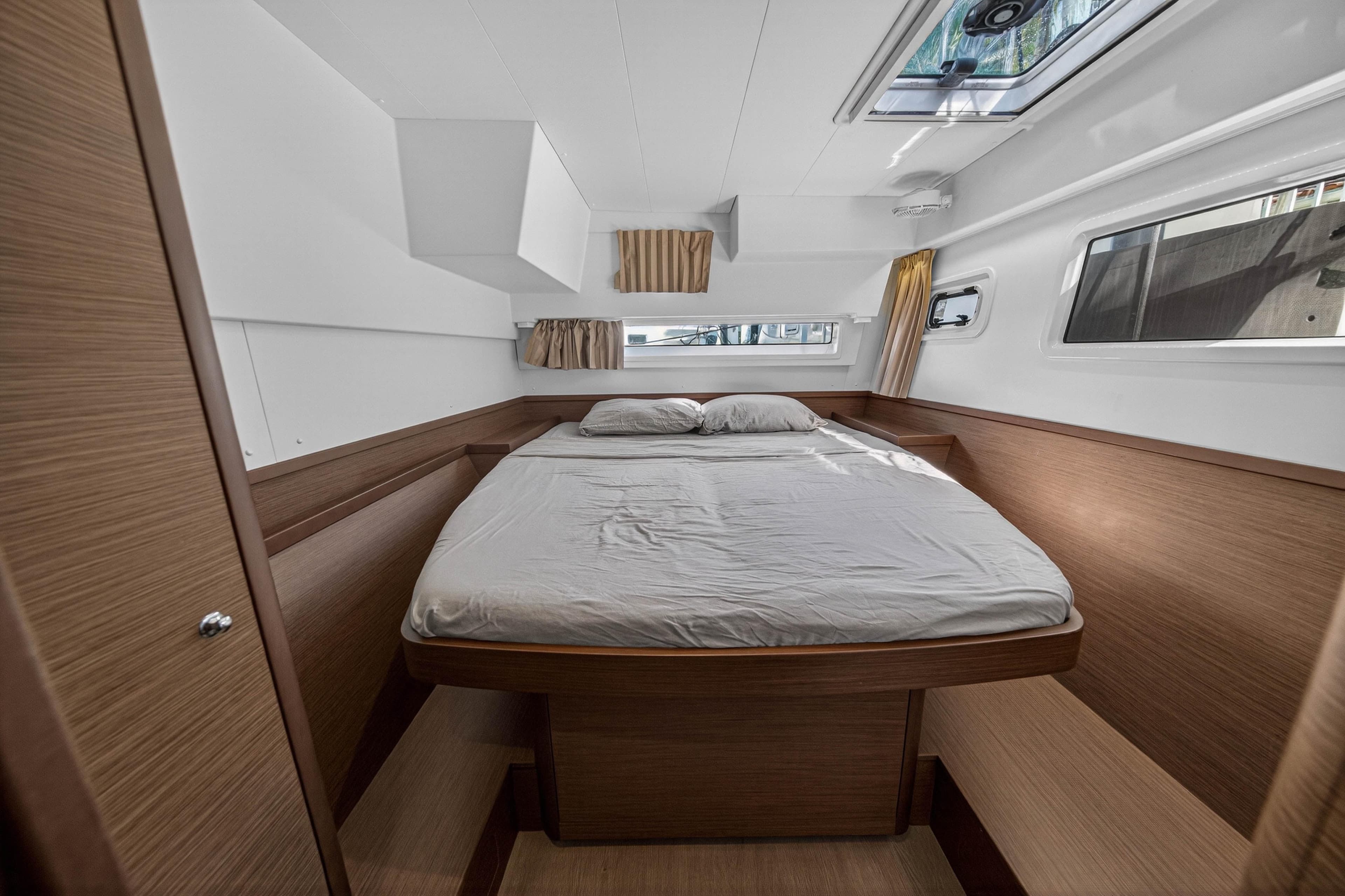 2019 Lagoon 42 yacht cabin with a cozy bed, wooden interior, and natural light.
