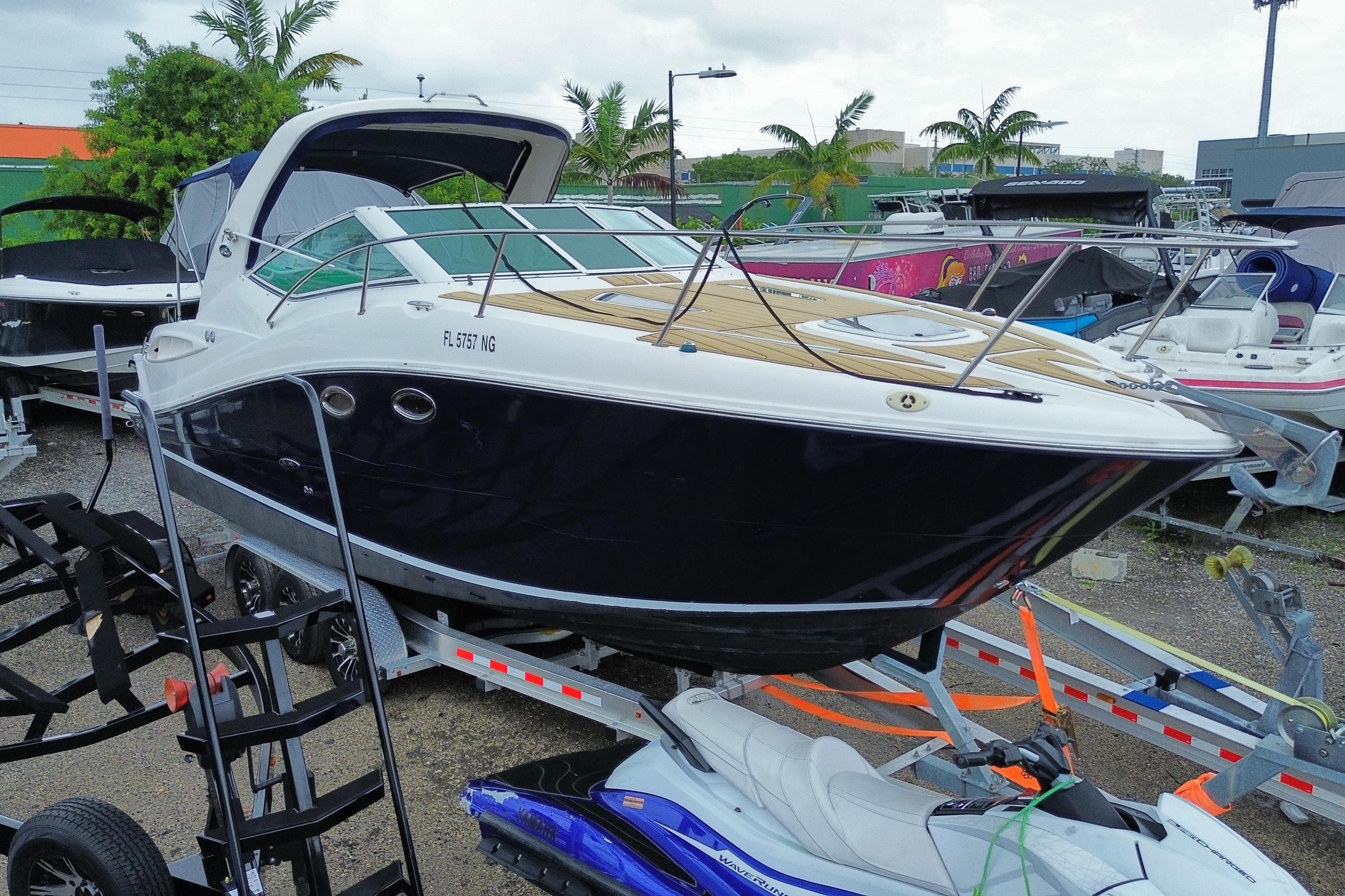 2006 Sea Ray 290 Sundancer boat on trailer, parked outdoors with palm trees in background.