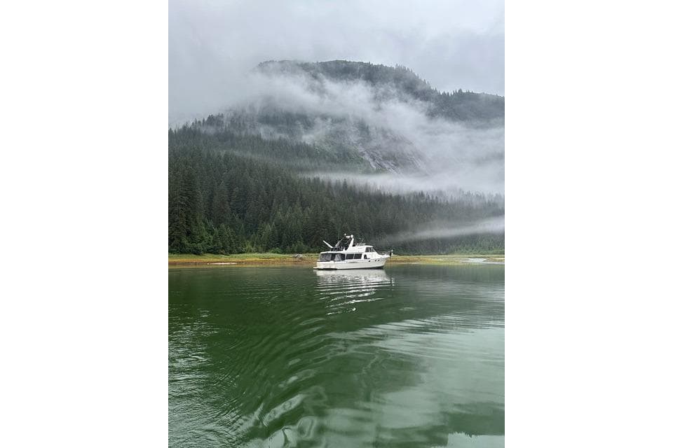 2003 Meridian 490 Pilothouse on misty lake with forested mountain backdrop.