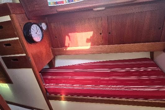 Interior of 1978 Tartan T34c sailboat with red-striped bunk and wooden cabinetry.