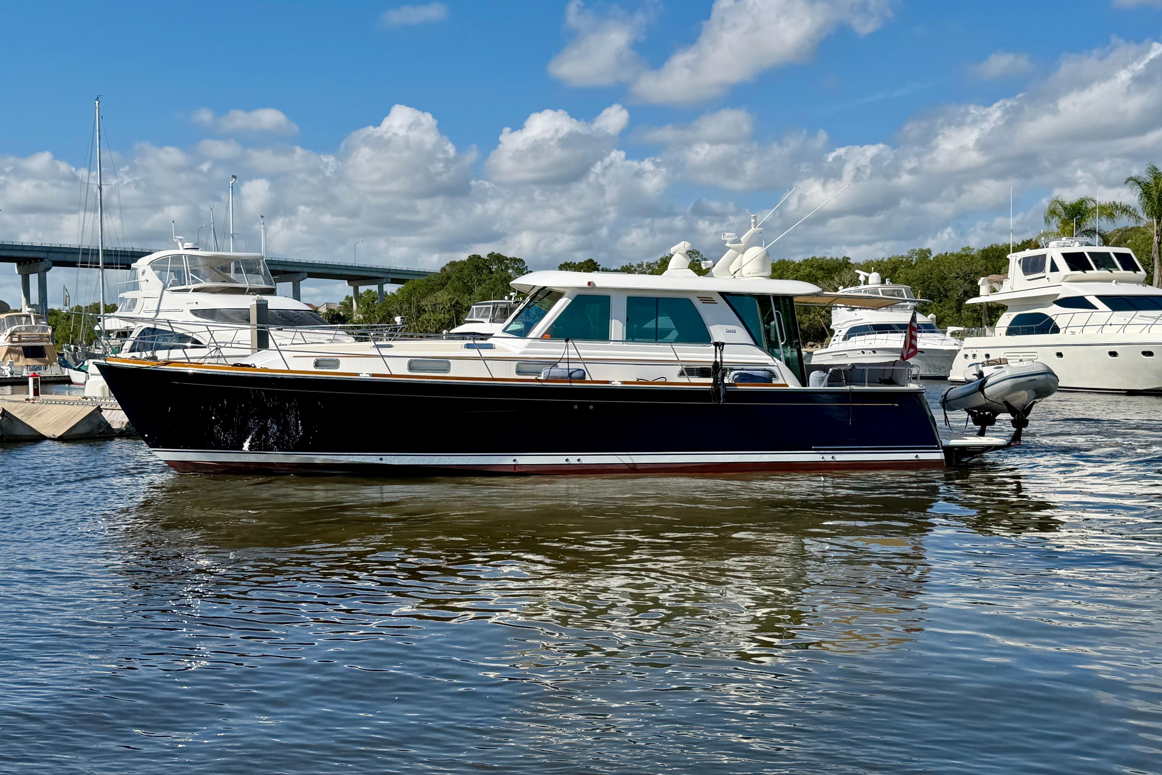 2016 Sabre 48 Salon Express yacht docked in a marina under a partly cloudy sky.
