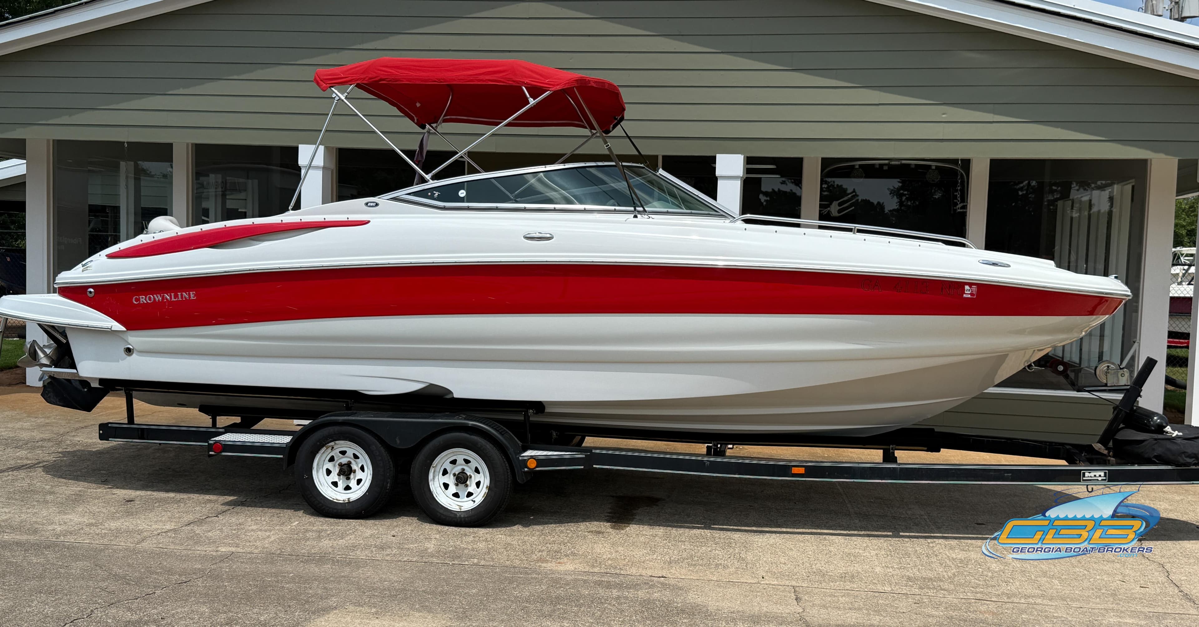 2006 Crownline 260 EX boat with red accents and canopy on a trailer.