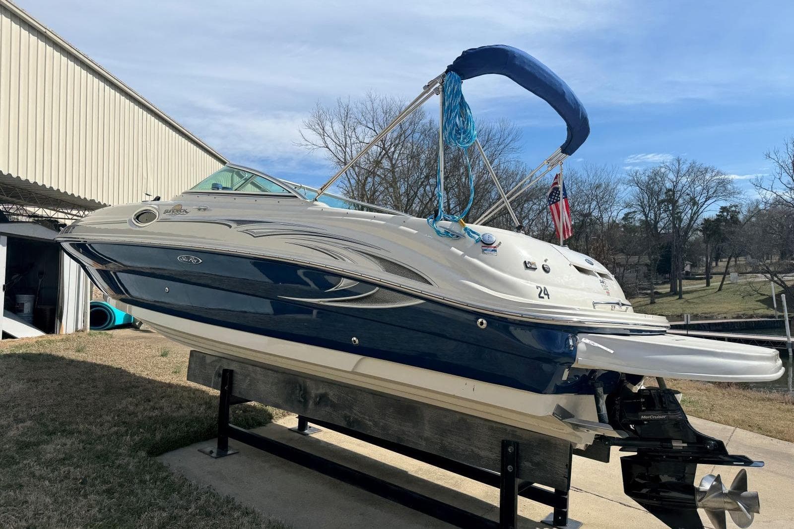 2006 Sea Ray 240 Sundeck boat on lift, blue and white exterior, sunny day.