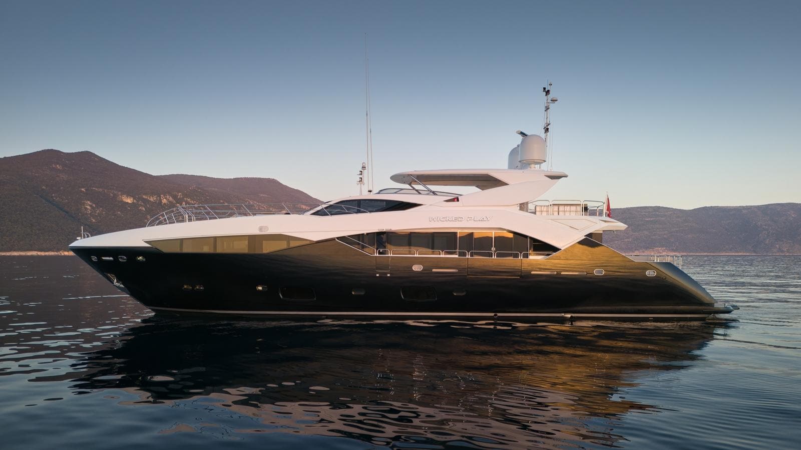 2015 Sunseeker 115 Sport Yacht on calm water, mountainous background.