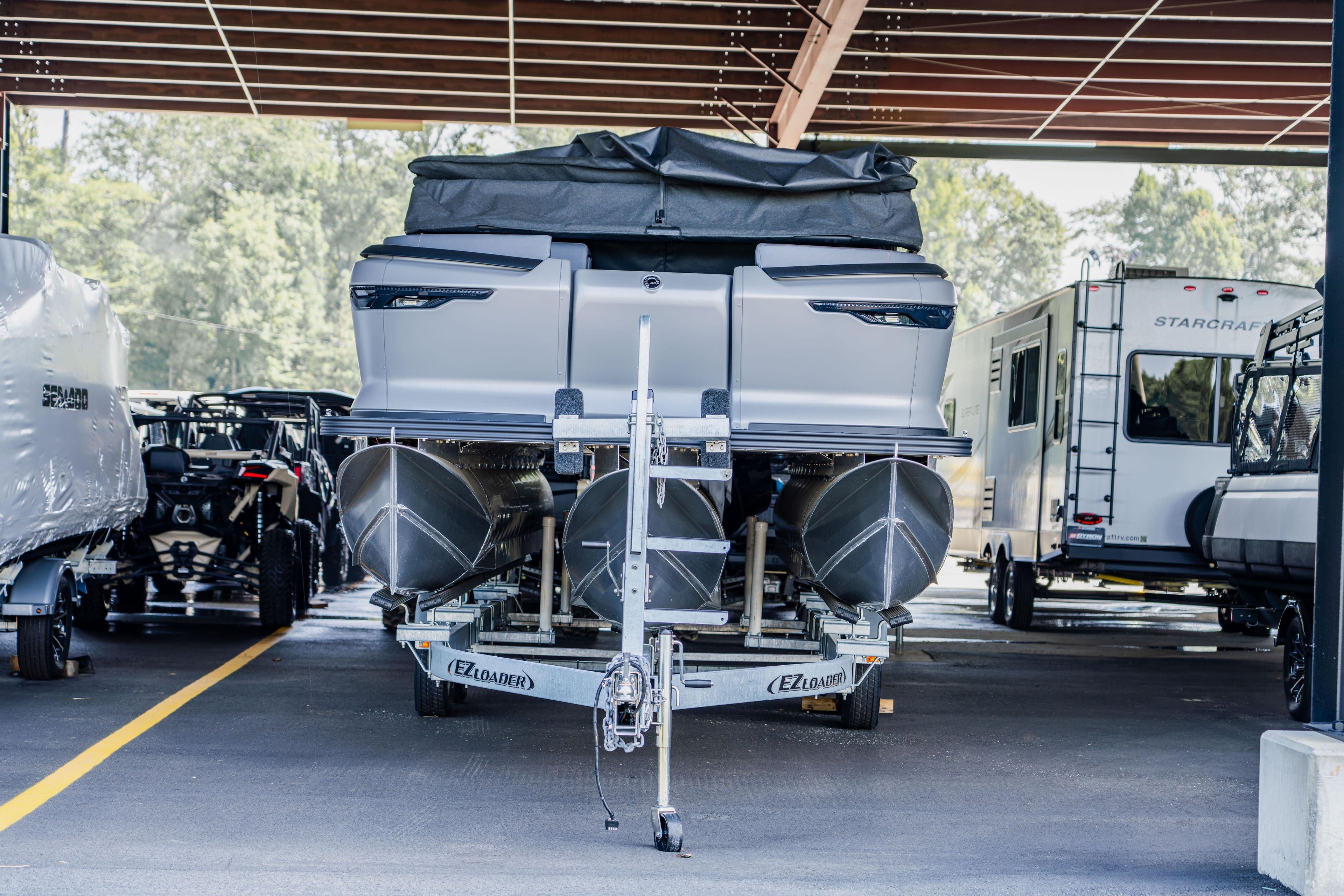 2023 Manitou 22 Explore Bench pontoon boat on trailer in covered storage.